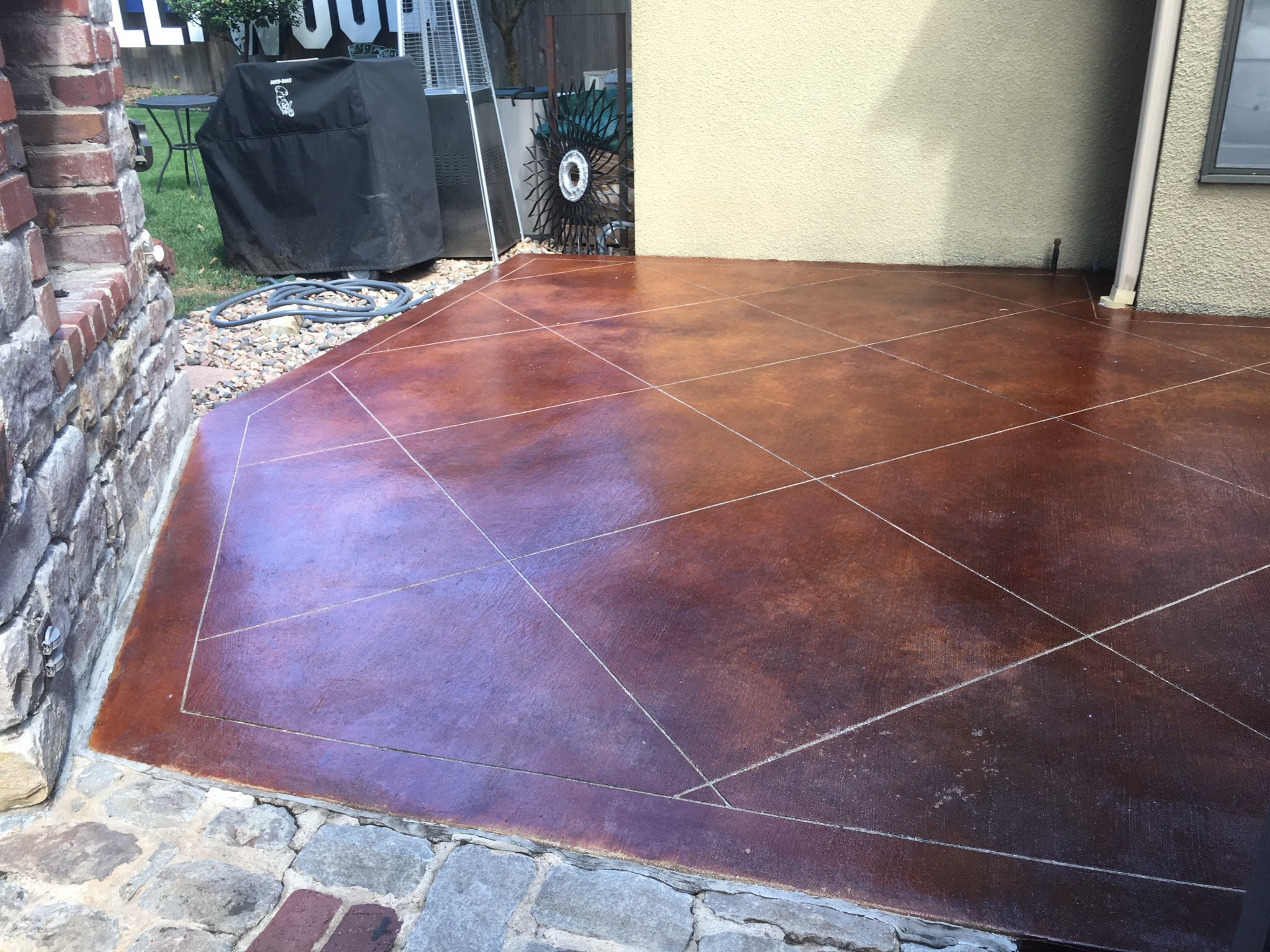 Beautiful custom stained concrete patio featuring a diamond scoreline pattern.