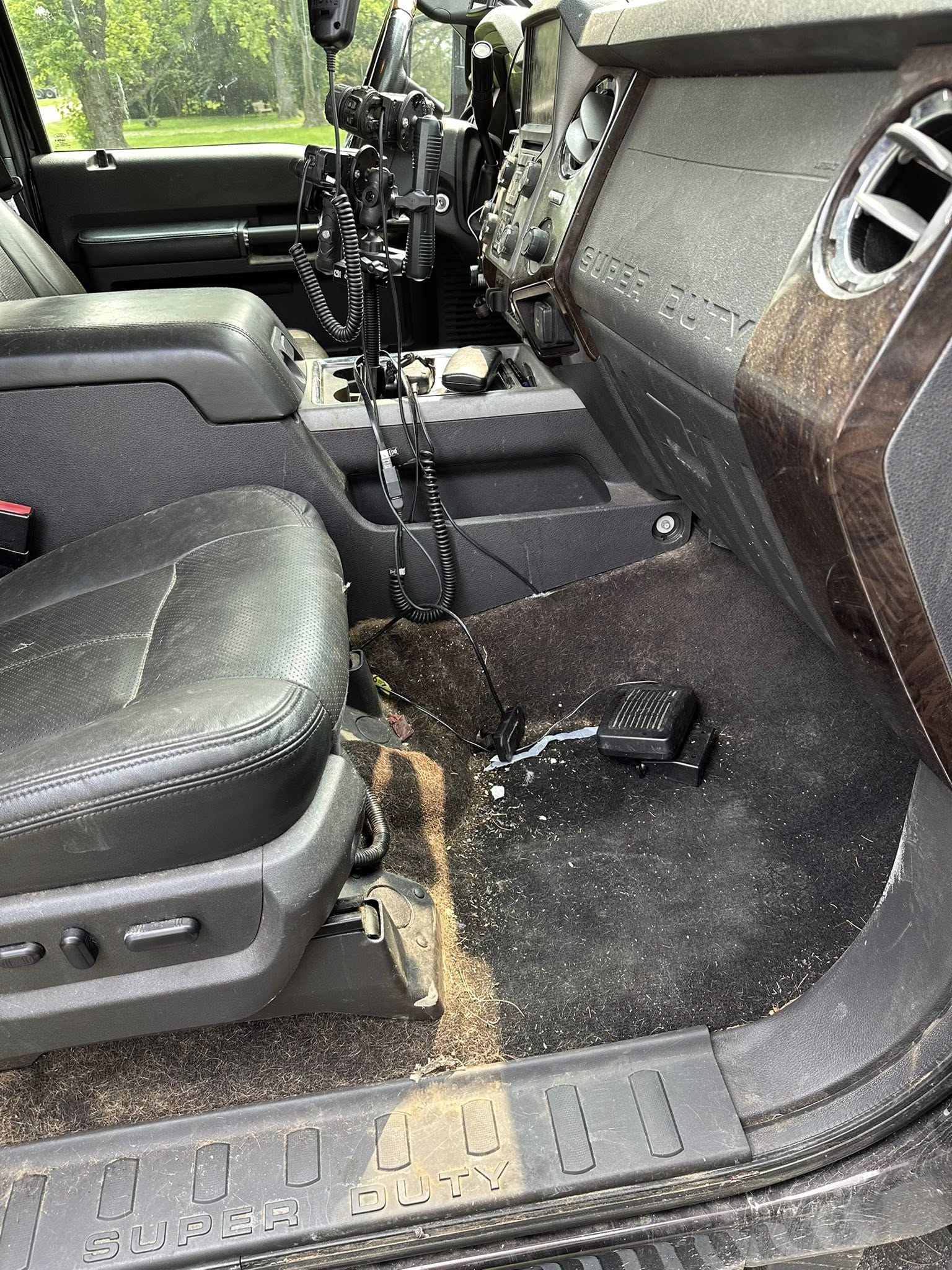 Work truck floorboard covered in grass clippings and debris before interior detailing