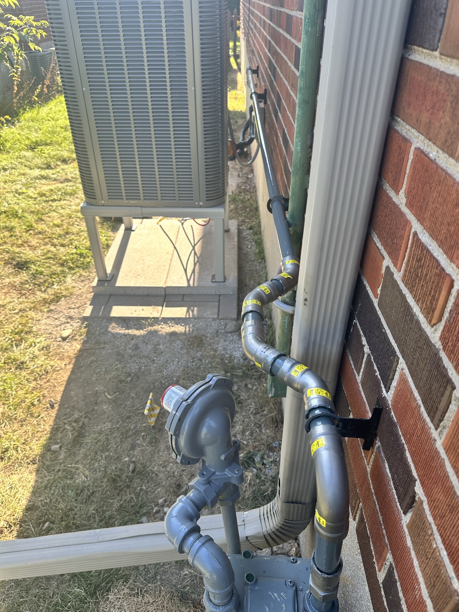 Exterior gas line and AC unit piping on brick home