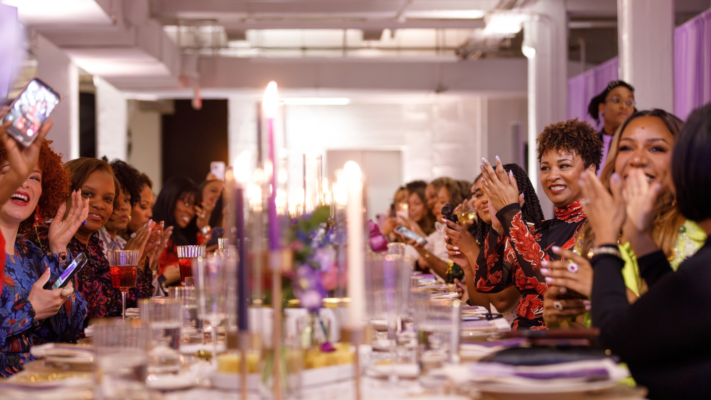 Banquet dinner guests applauding and celebrating by candlelight