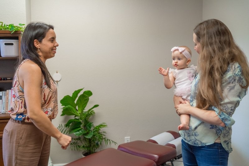 Dr. Liz welcoming a mother and infant for an evaluation at Mojica Chiropractic Care