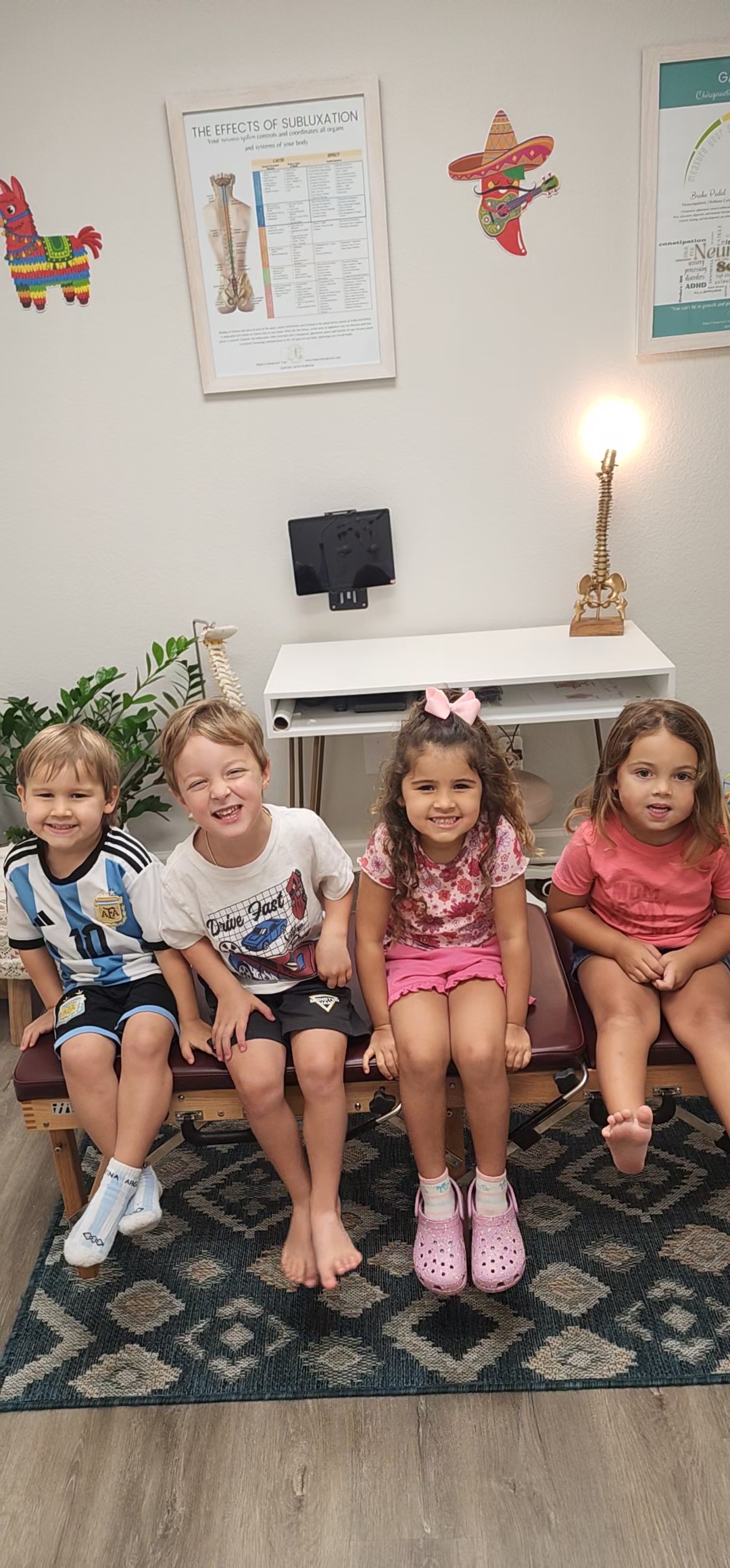 Children sitting together cheerfully on a treatment bench at Mojica Chiropractic Care during developmental evaluation