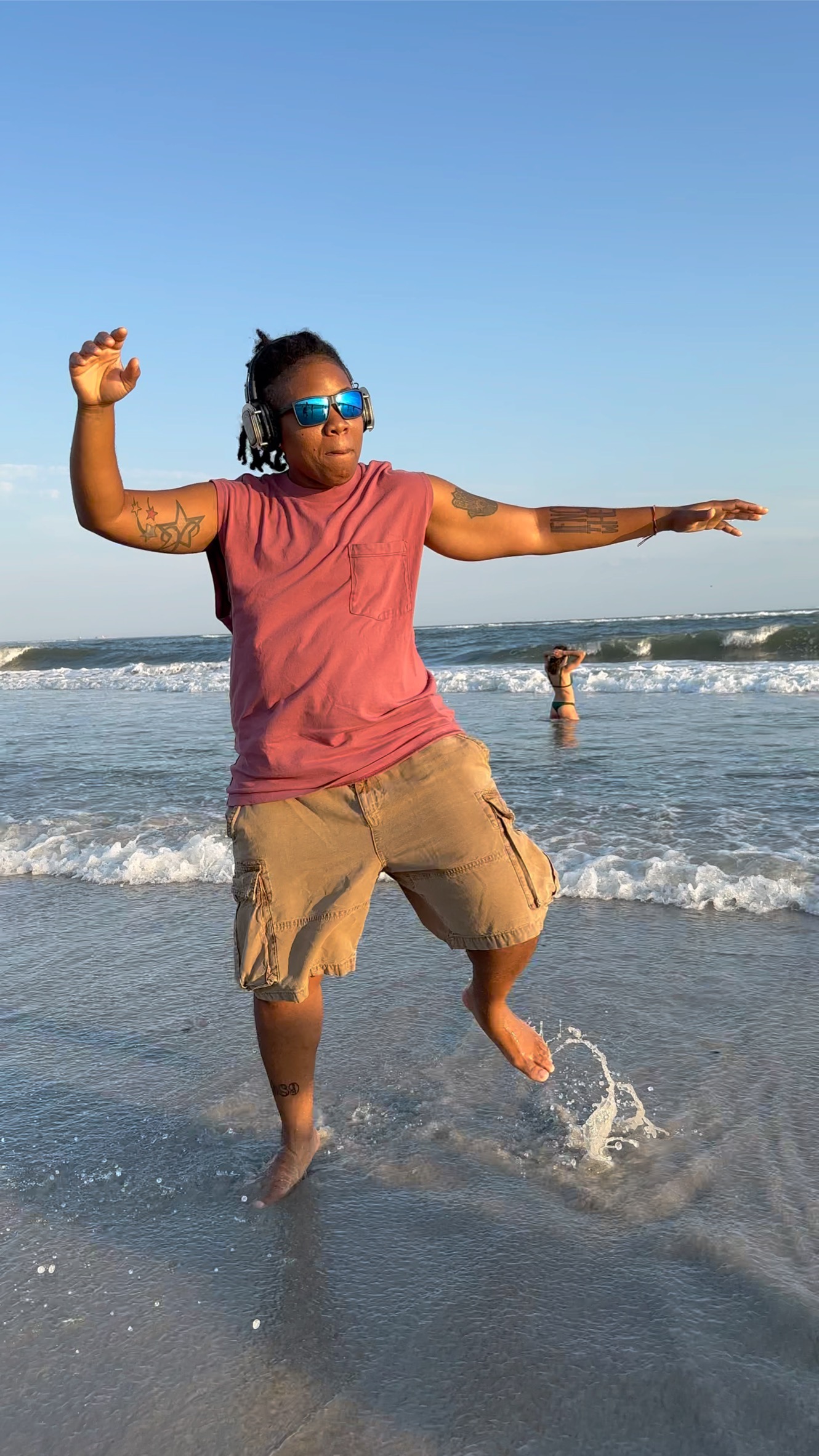 Destinē dancing freely in the ocean surf with headphones on