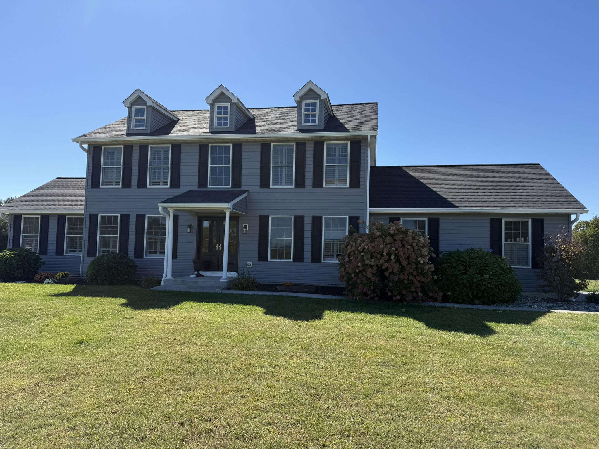 Gray Siding & Roofing - Complete exterior update featuring new gray siding, dark shutters, and a fresh roof.
