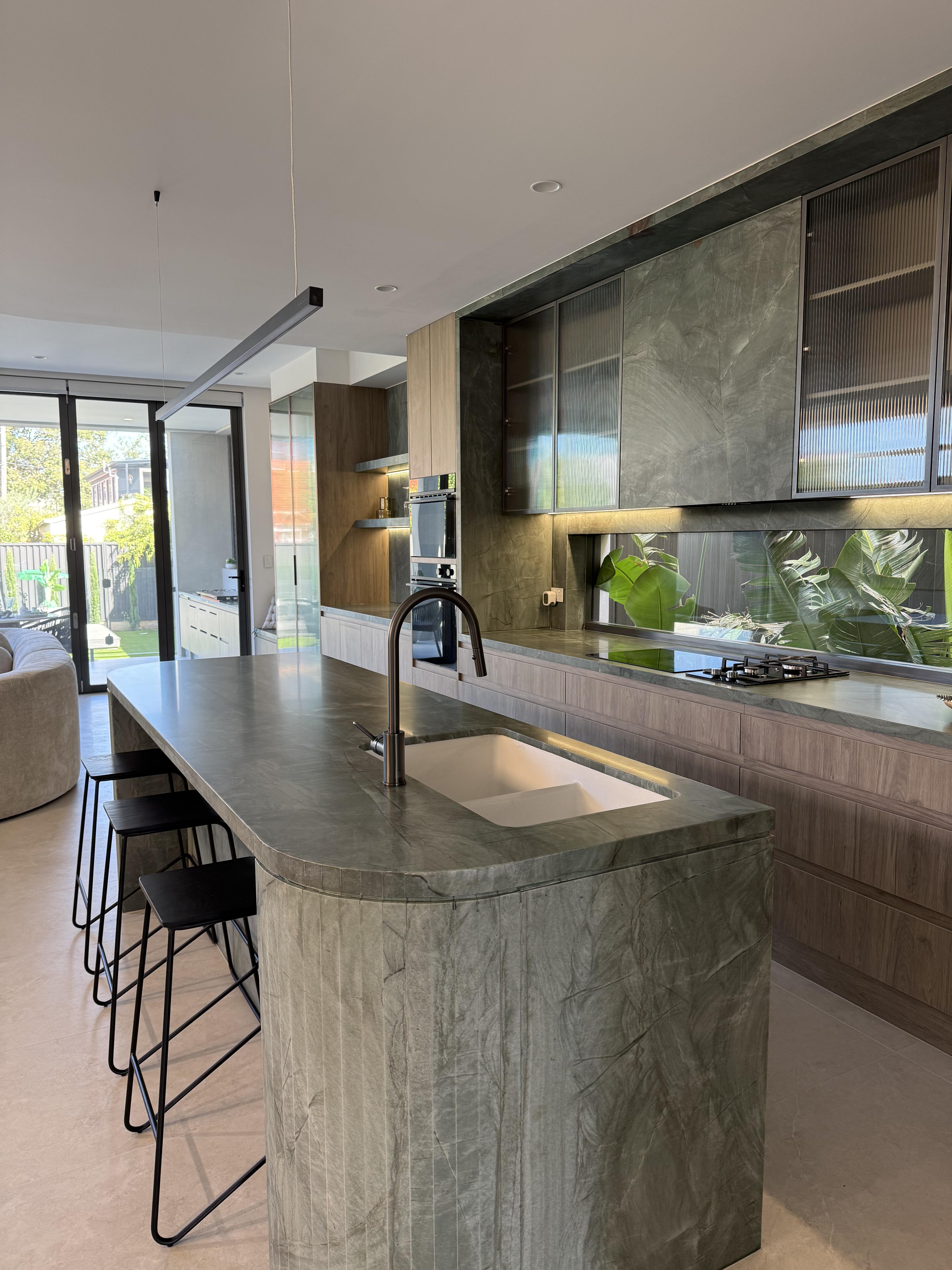 Modern kitchen with dark green marble island and fluted base, stone protection film by Pro Surface Protection