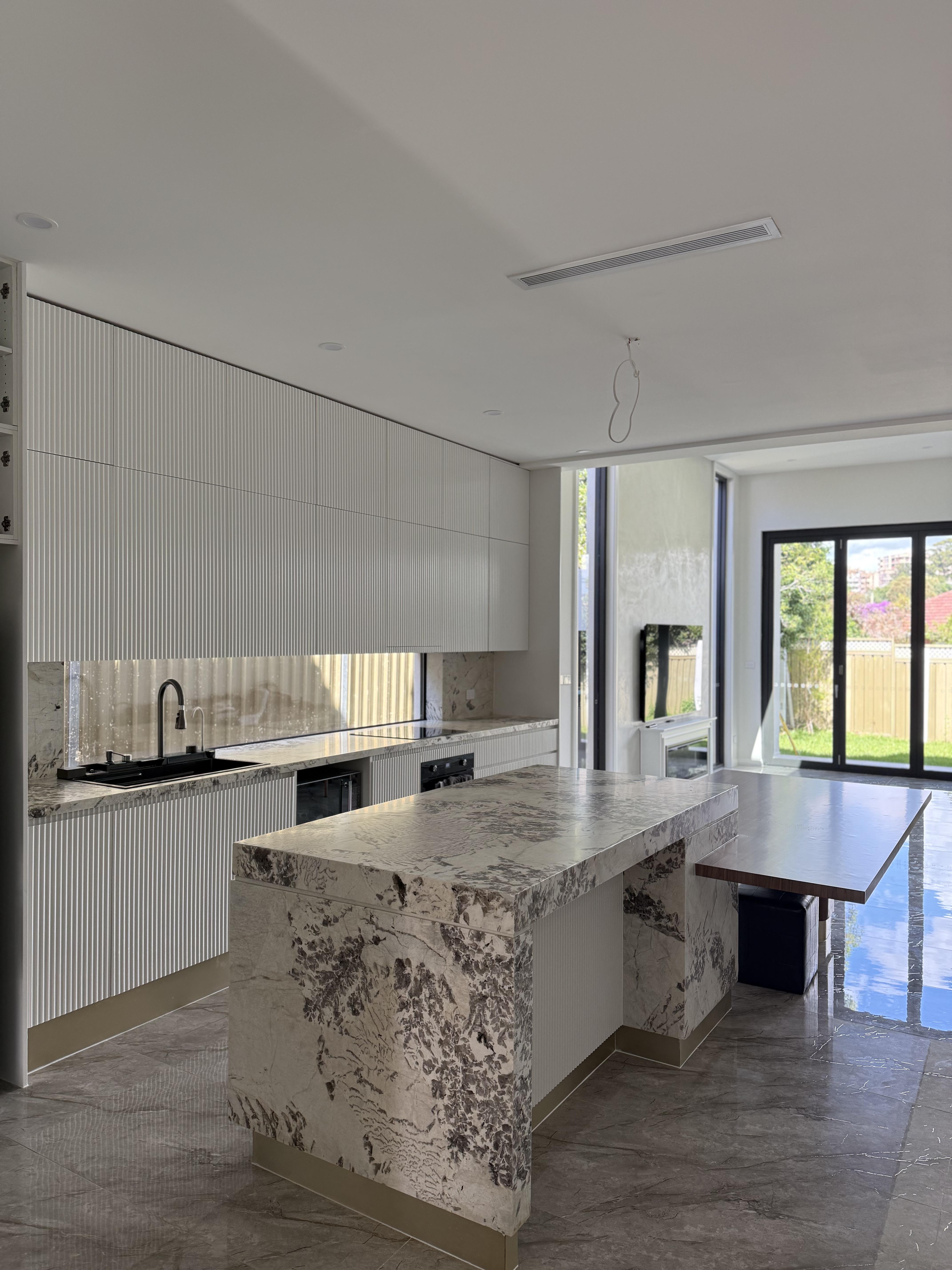 Modern white kitchen with granite benchtop and fluted cabinetry, stone protection film by Pro Surface Protection