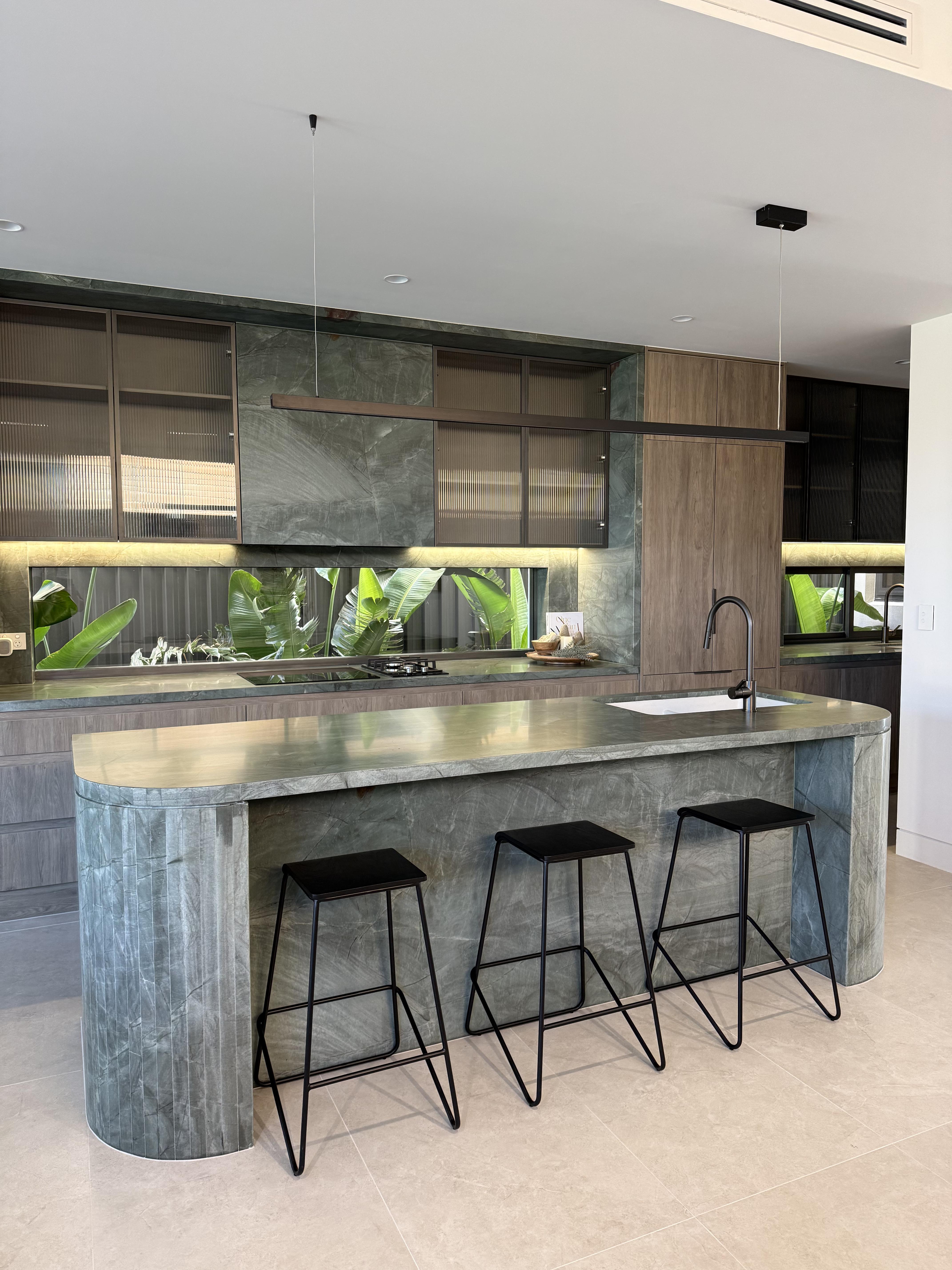 Sleek grey stone kitchen island with black bar stools, surface protection film applied by Pro Surface Protection