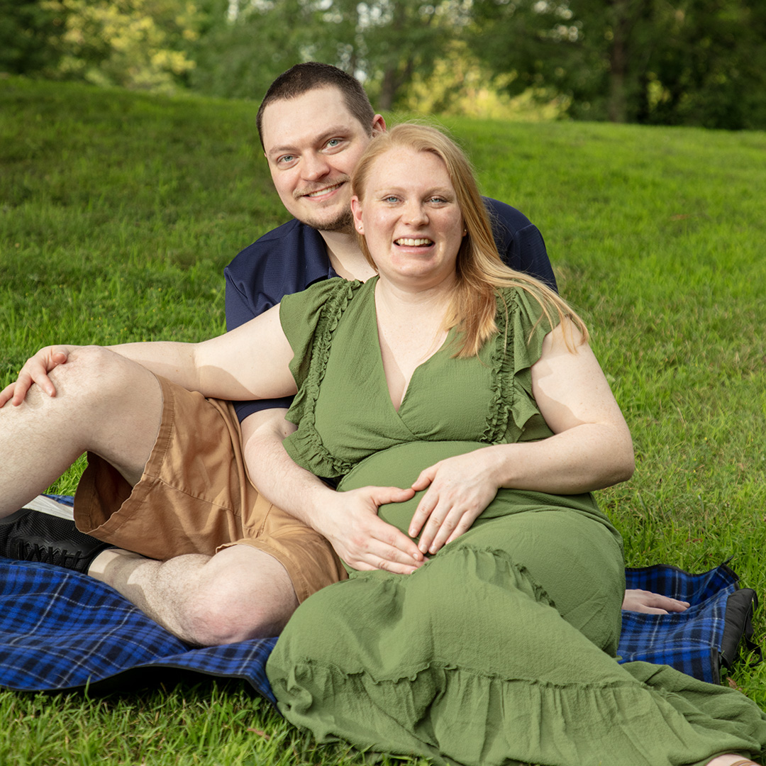 Expecting couple sitting on a blanket in the grass