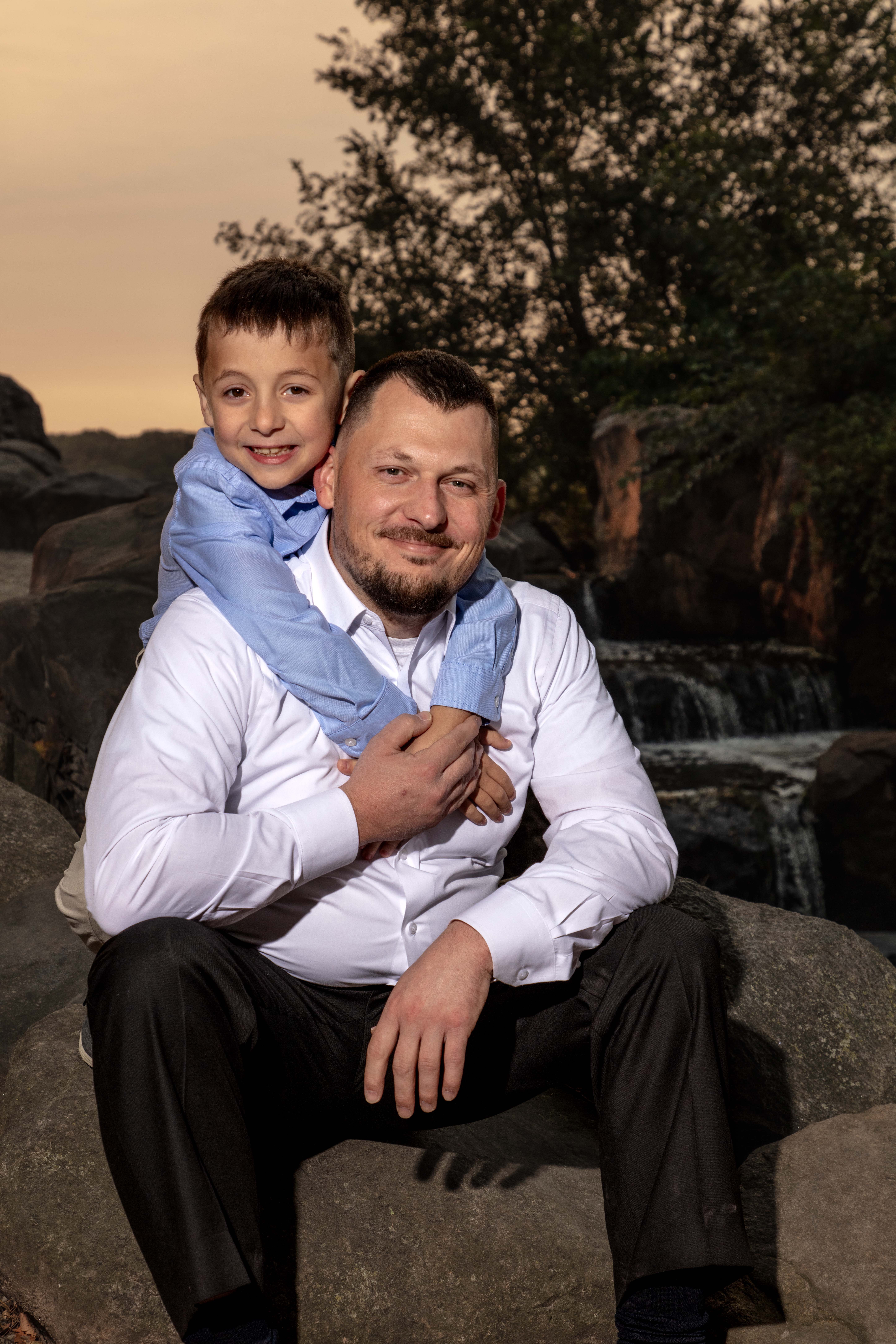 Father and son sitting on rocks by a stream