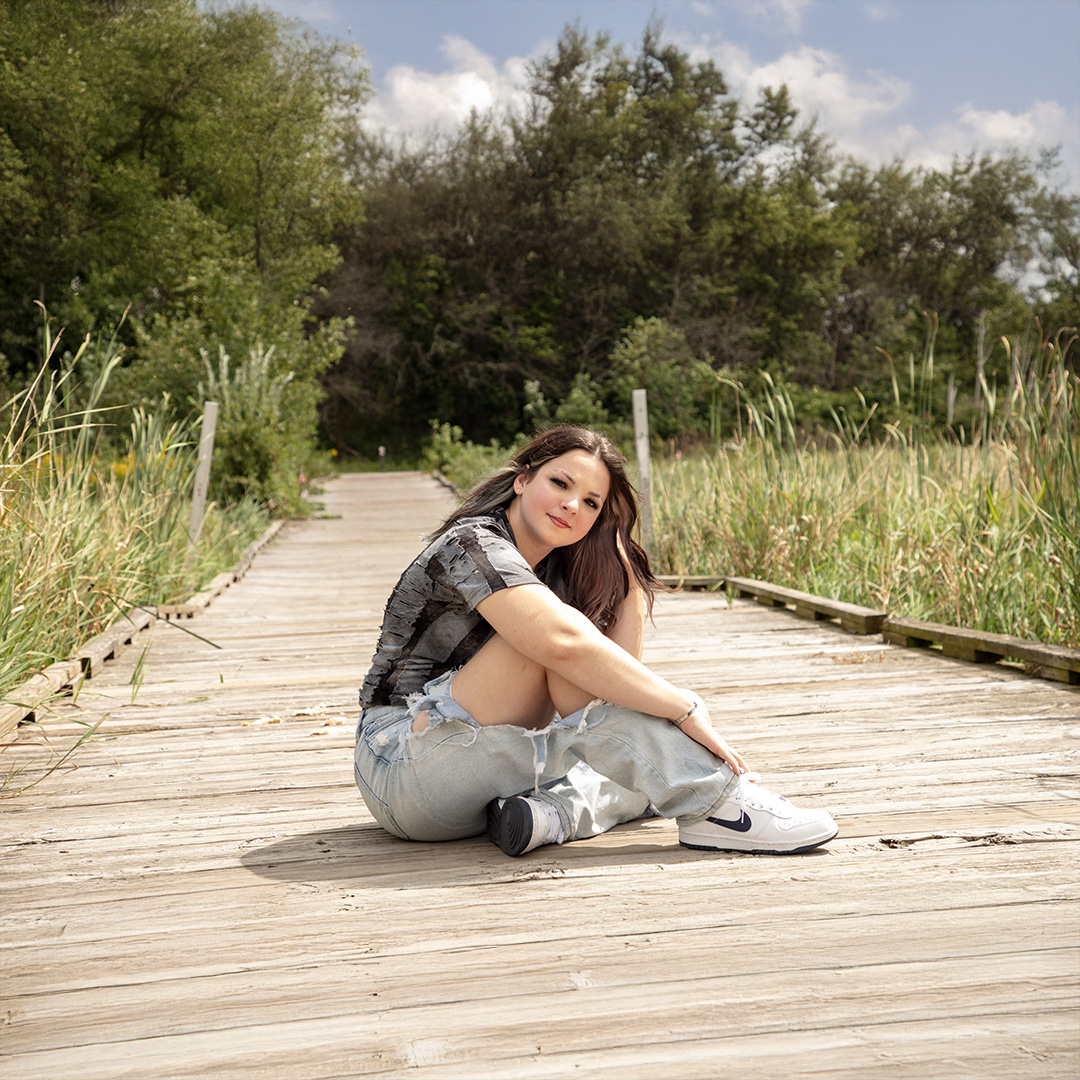 Senior girl sitting on a wooden boardwalk in nature