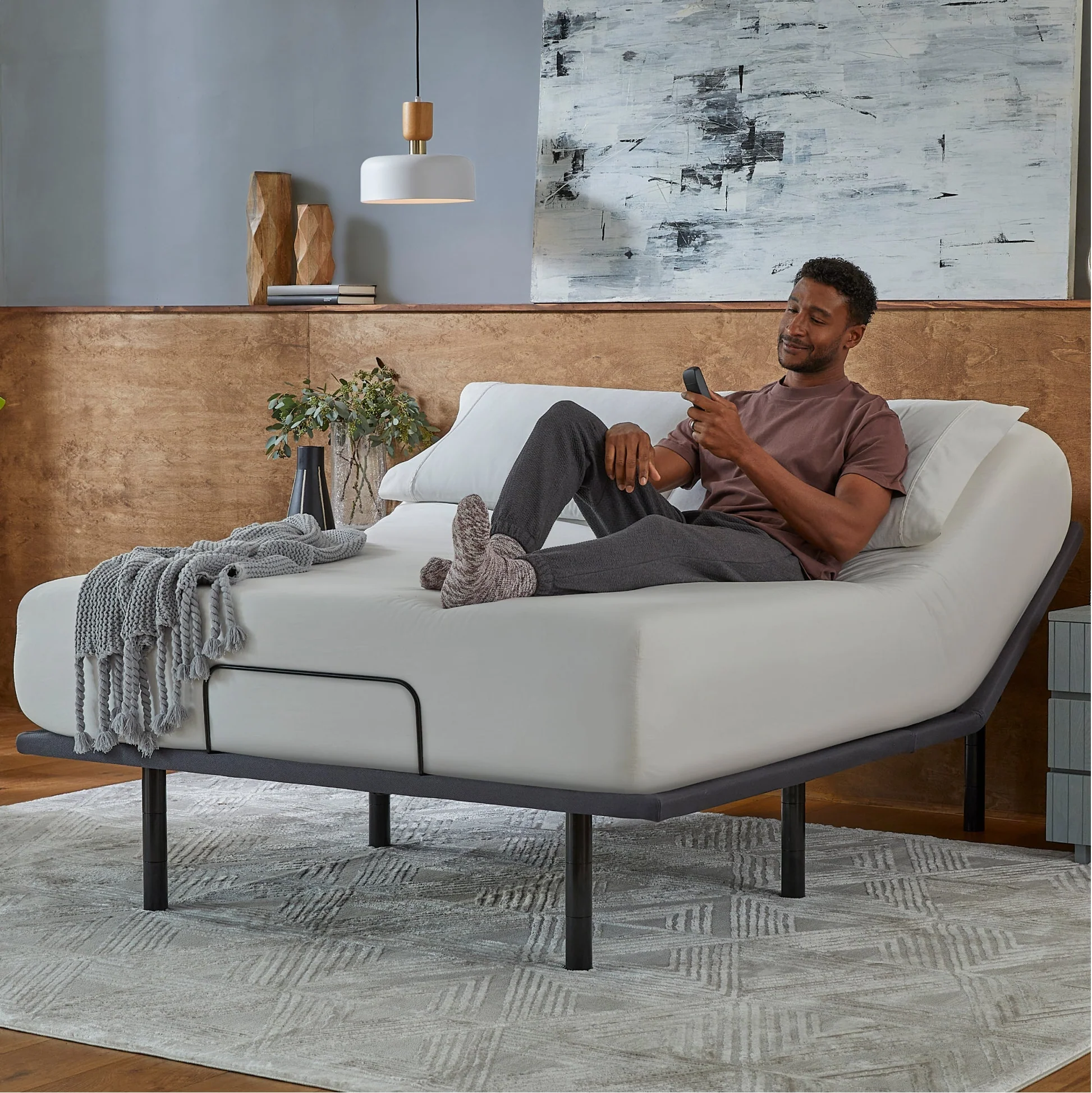 Person relaxing on power adjustable bed base with wireless remote