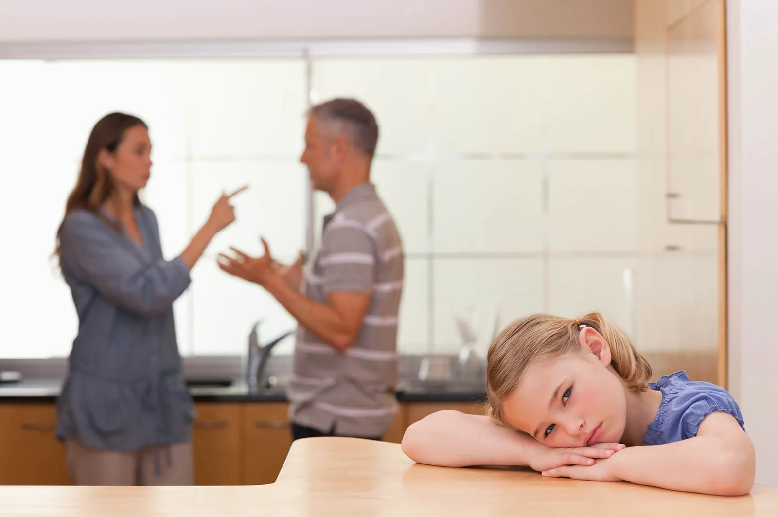 Sad little girl listening to her parents argue, representing the impact of divorce on children.