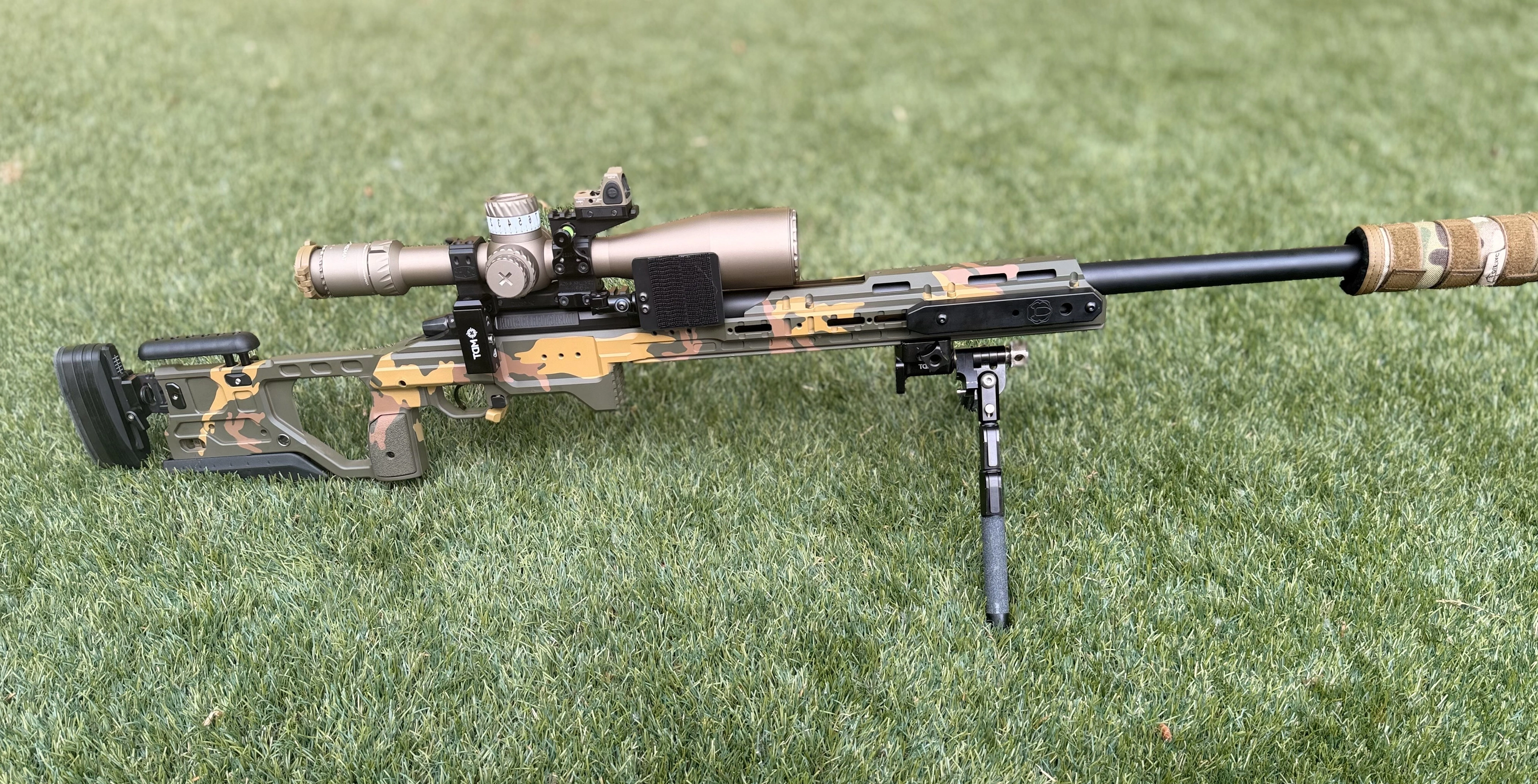 Custom camouflaged precision rifle on grass