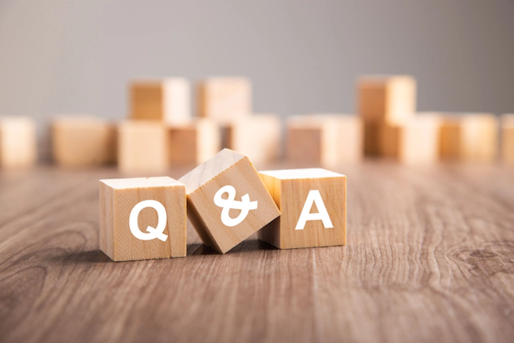 Wooden blocks spelling Q and A on a wooden table surface representing questions and answers
