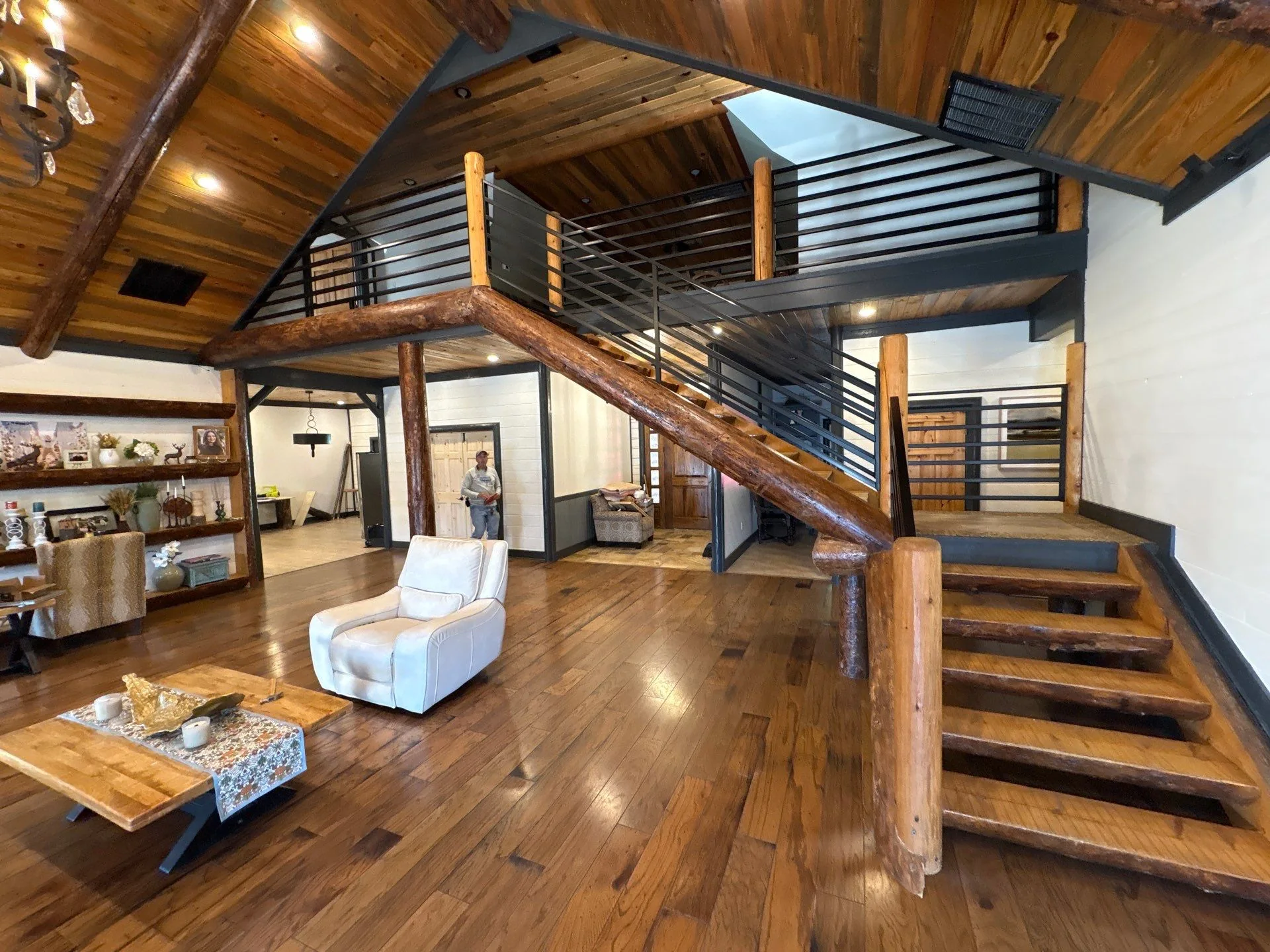 Two-story great room with timber staircase, wooden steps, metal railings, and exposed ceiling beams