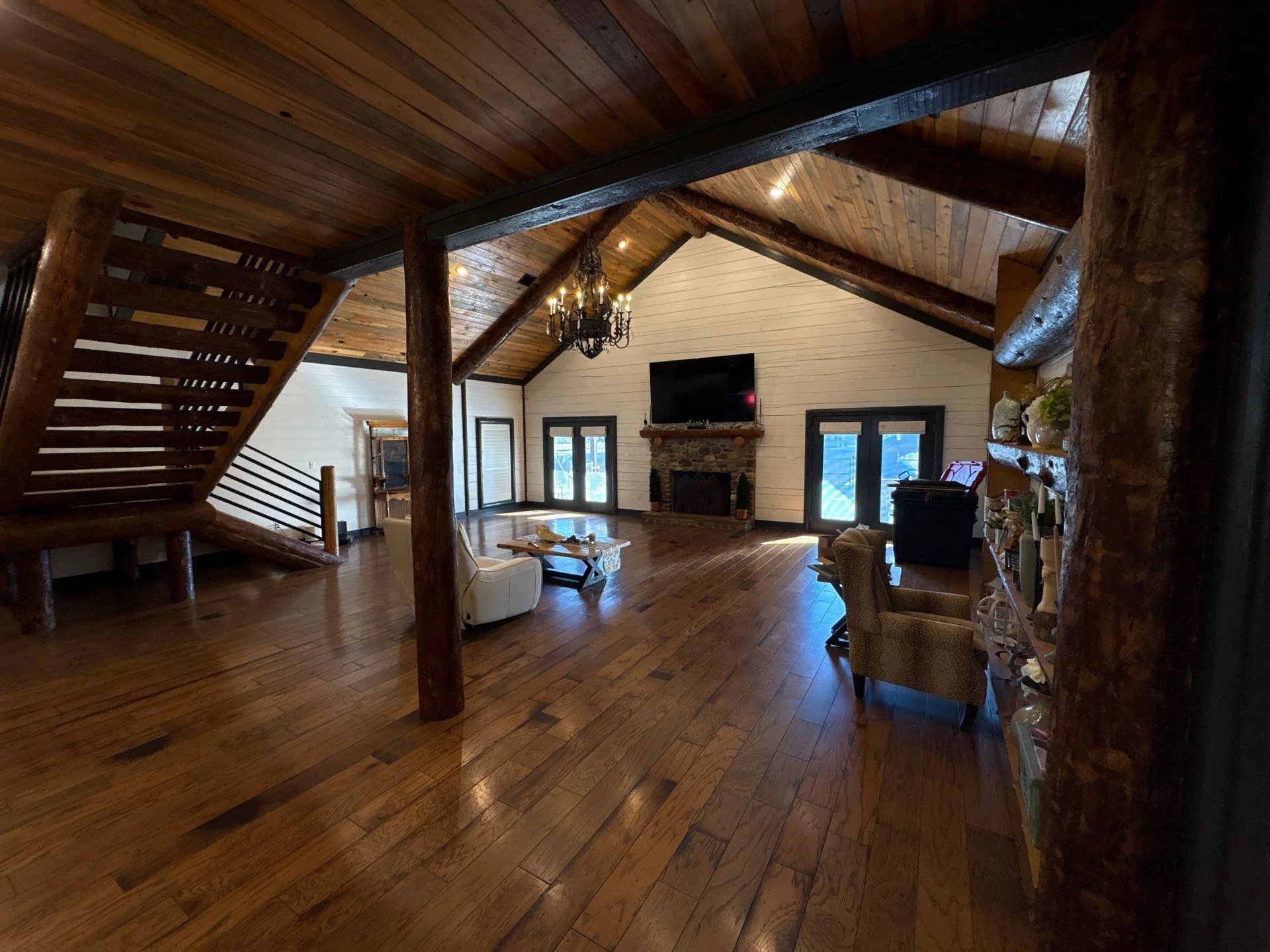 Living space with timber staircase, wood paneled ceiling, stone fireplace, and light floors