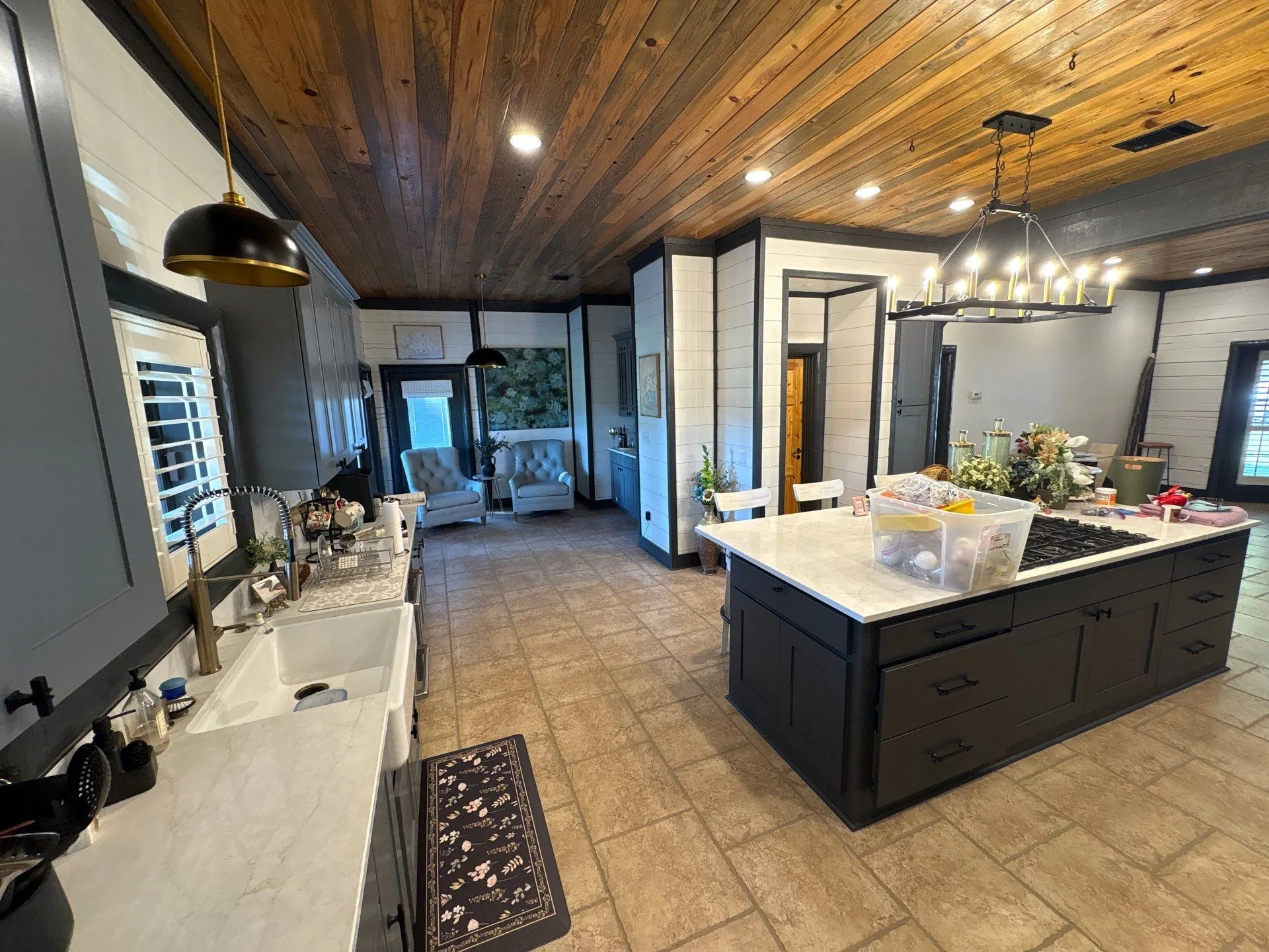 Kitchen and living area with light walls, dark trim, cabinetry, and wood ceiling with pendant lights