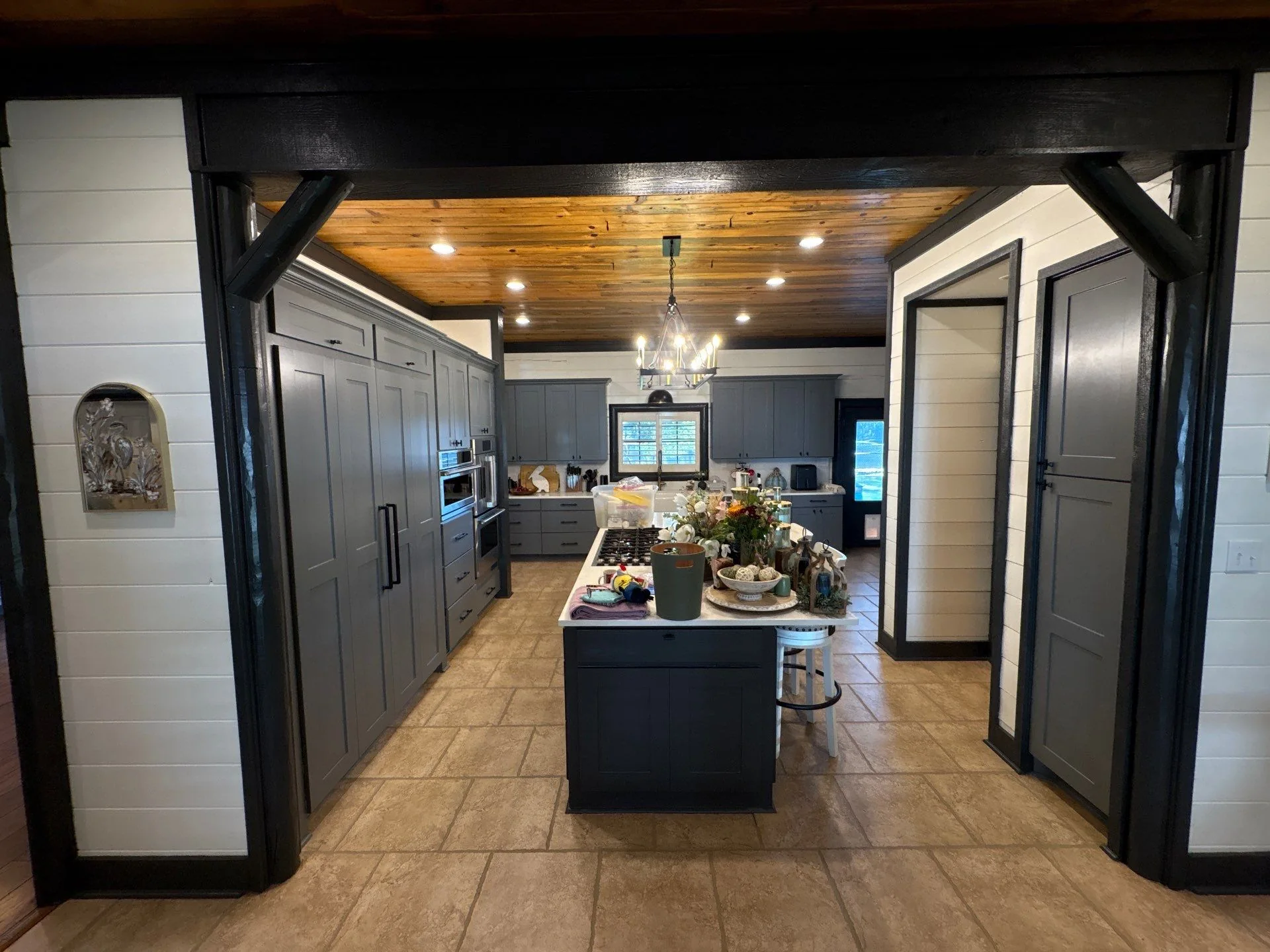 Kitchen with gray cabinetry, central island, light countertop, and wood ceiling with chandelier