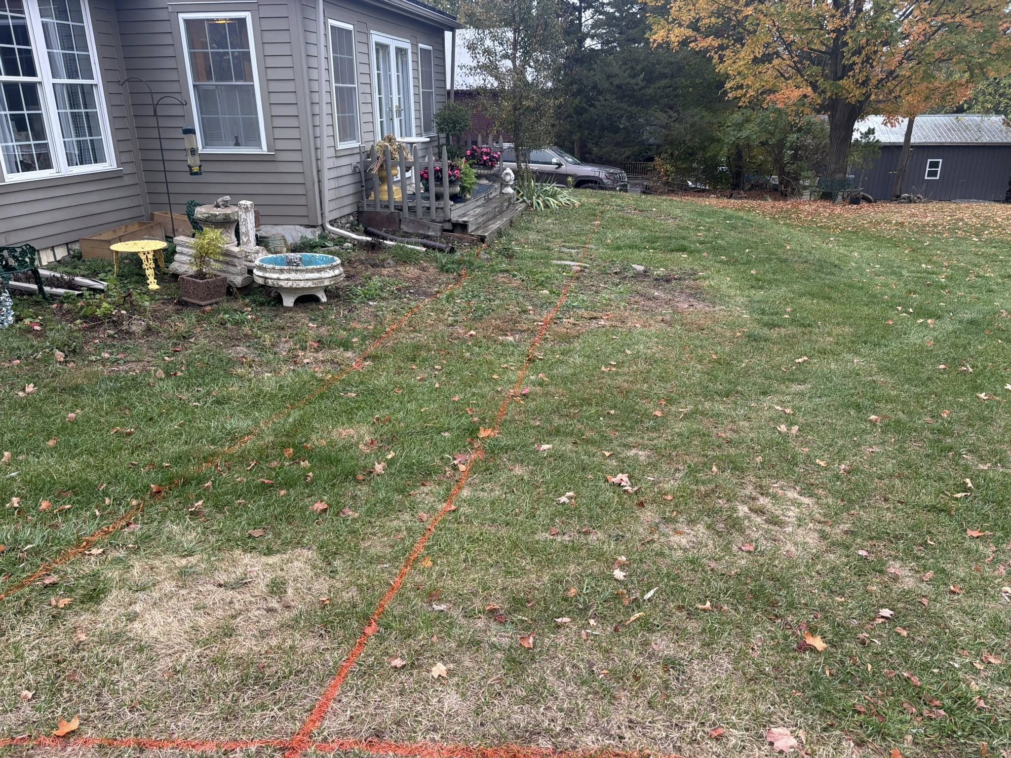 Orange marking paint on grass near house for site prep
