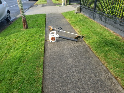 Neat footpath edging beside lush green lawn with STIHL blower