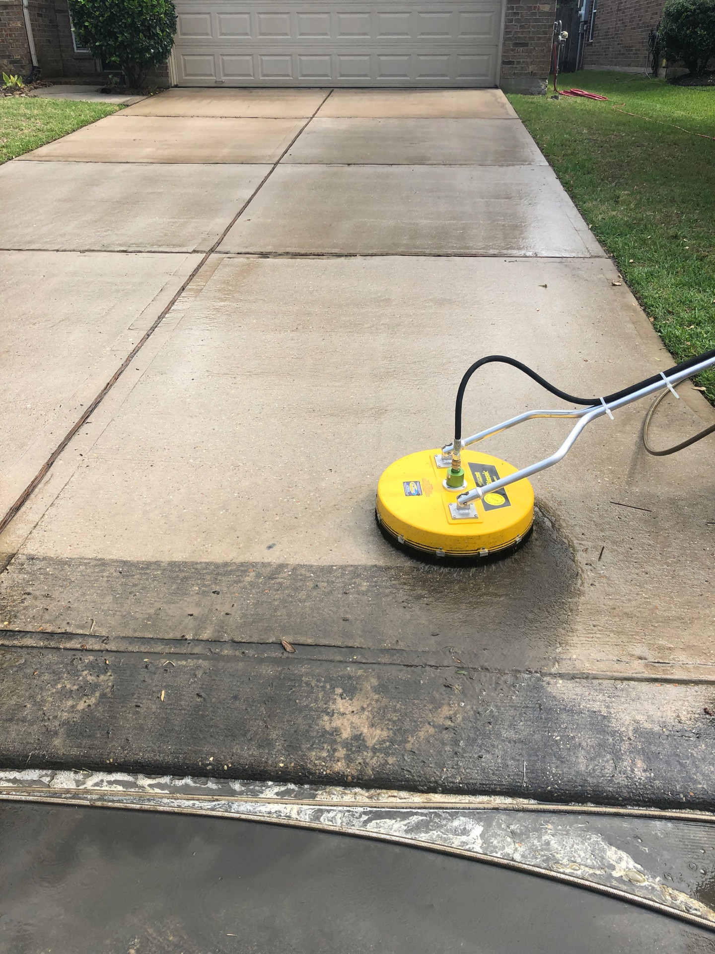High pressure rotary surface cleaner washing a concrete driveway