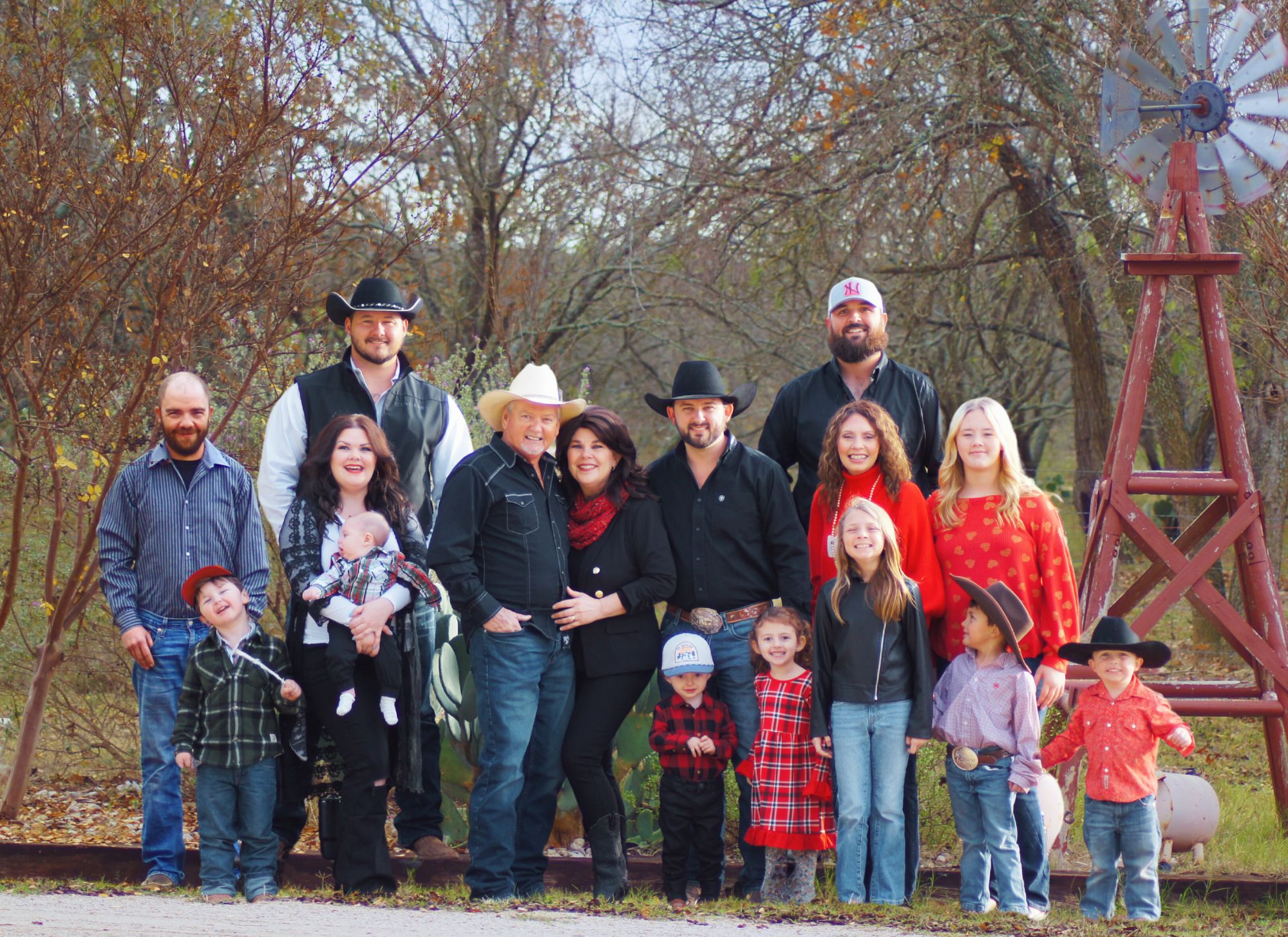 Family portrait in a natural outdoor setting, featuring multiple generations smiling together, with adults in western attire and children dressed in festive outfits, symbolizing unity and joy in personal healing and family support.