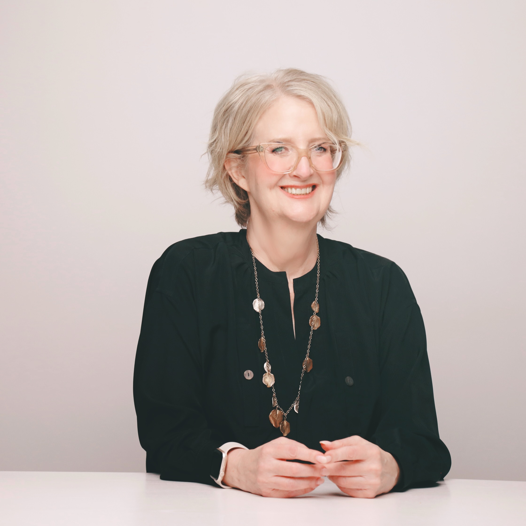 Meg Crumbine, go-to-market coach, seated by fireplace