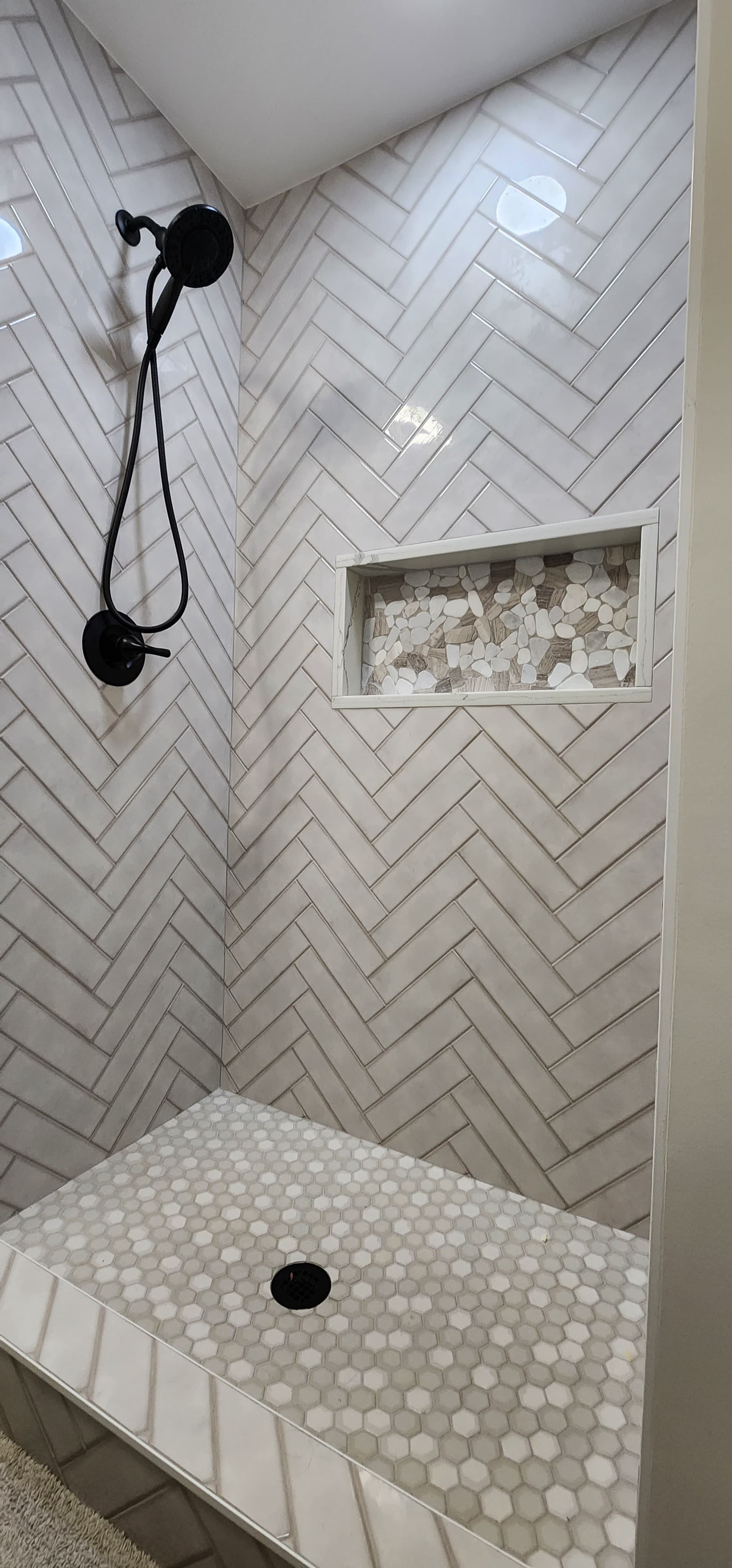 Custom Walk-in Shower with Herringbone Wall Tile, River Stone Niche & Hex Floor