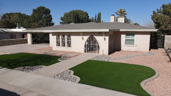 Front yard turf installation with custom metal gate and decorative rock beds