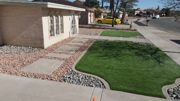 Completed turf installation with decorative rock border and concrete walkway in El Paso
