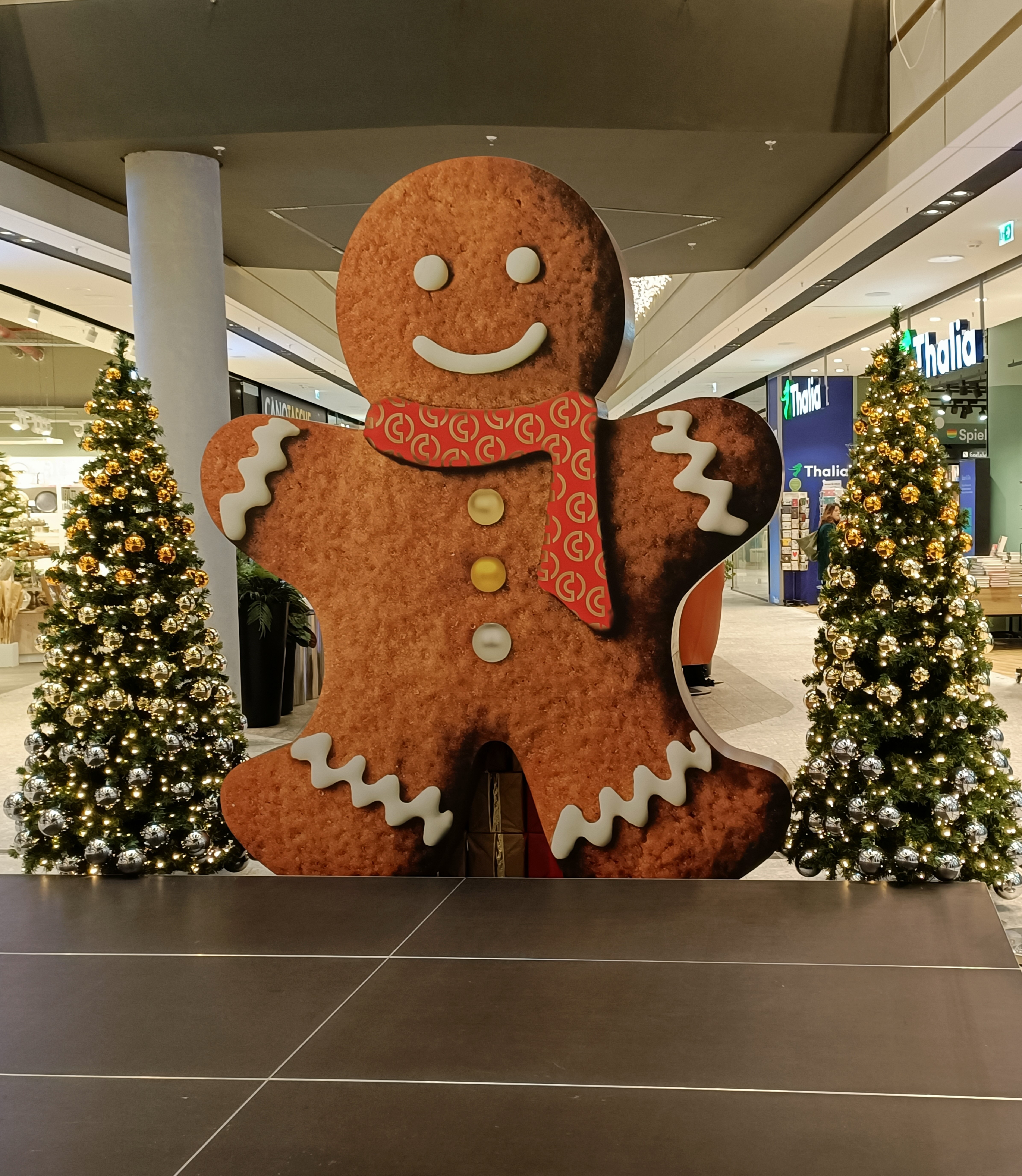 Weihnachtsdeko im Einkaufszentrum mit Lebkuchenmann und geschmückten Weihnachtsbäumen
