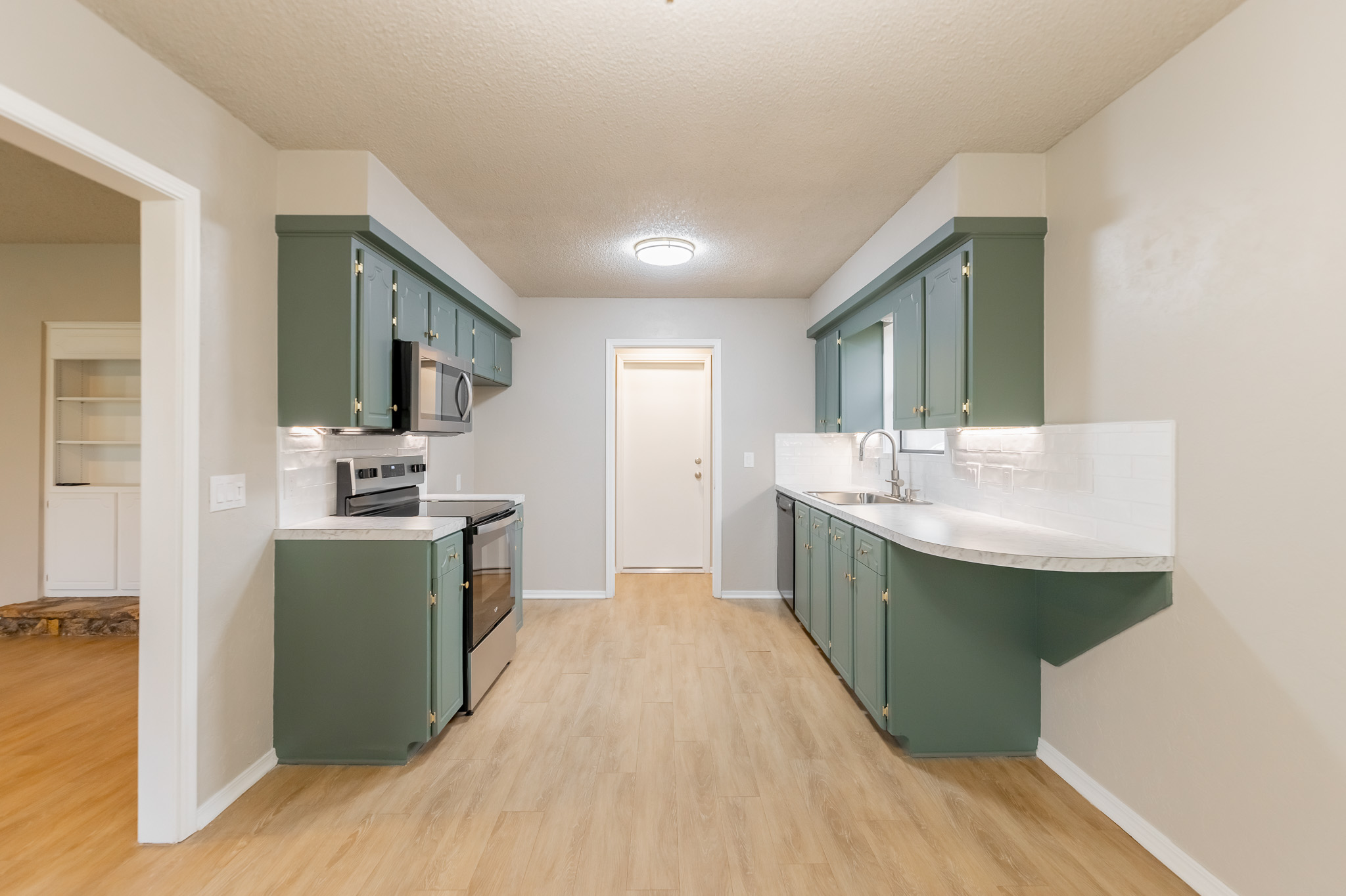Kitchen after renovation - sage green cabinets and quartz countertops by Renovate Stillwater