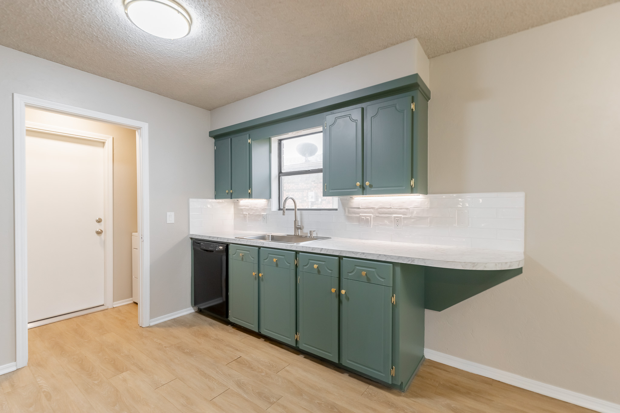 Renovated kitchen detail showing green cabinetry and gold hardware by Renovate Stillwater