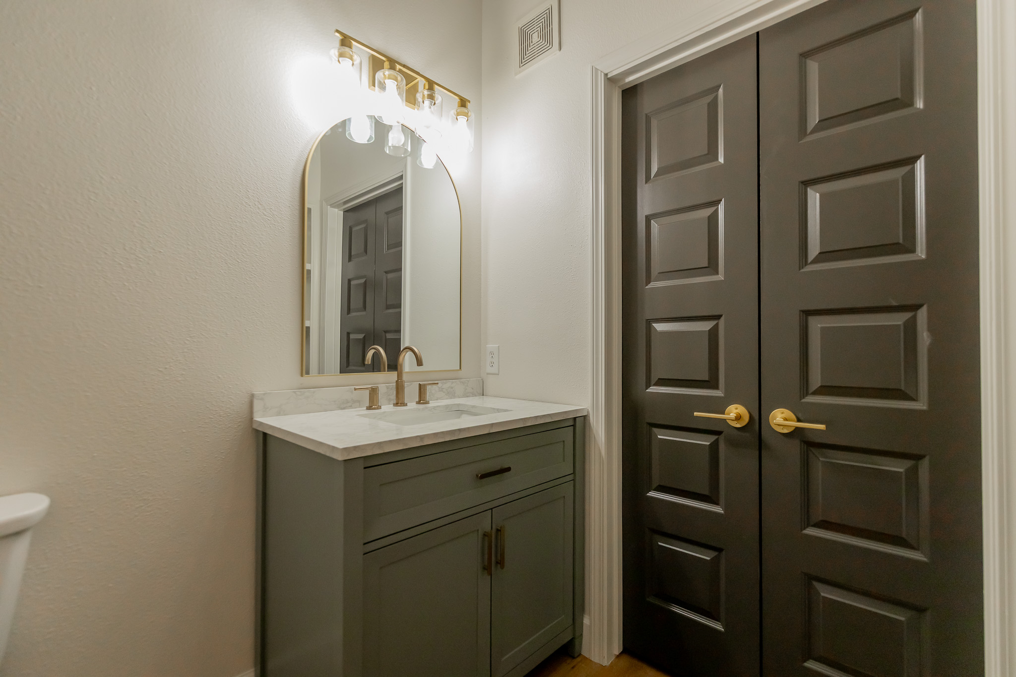 Bathroom remodel with green vanity and gold fixtures by Renovate Stillwater in Stillwater, OK