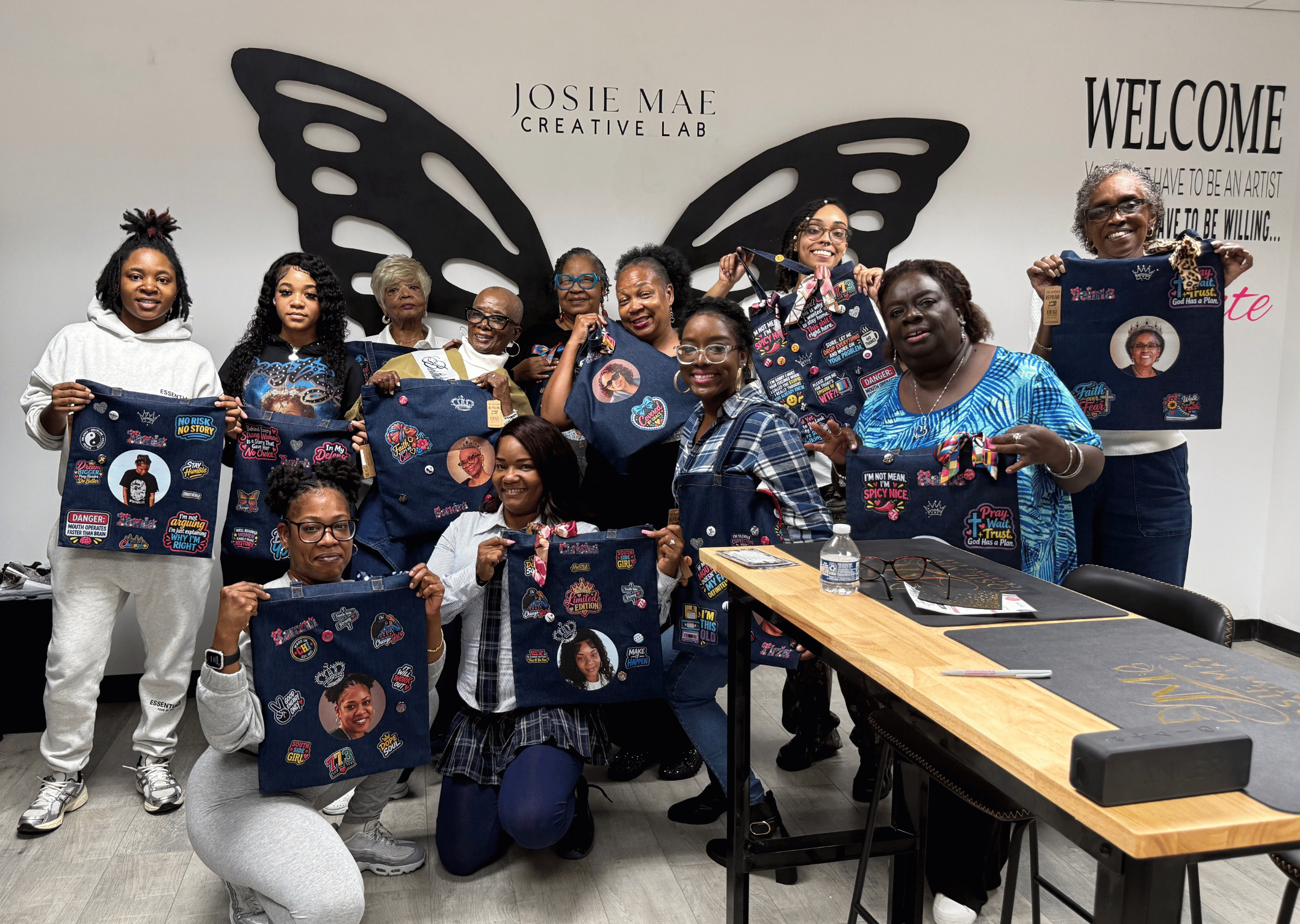 Guests celebrating and showcasing their custom Junk Totes in front of the Josie Mae Creative Lab butterfly wings