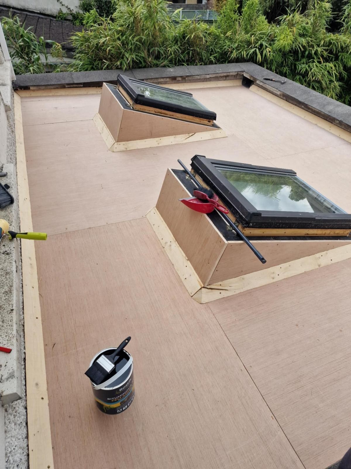 Plywood flat roof deck ready for felt, with a tin of bitumen primer and brush, in Walkinstown, Dublin 12