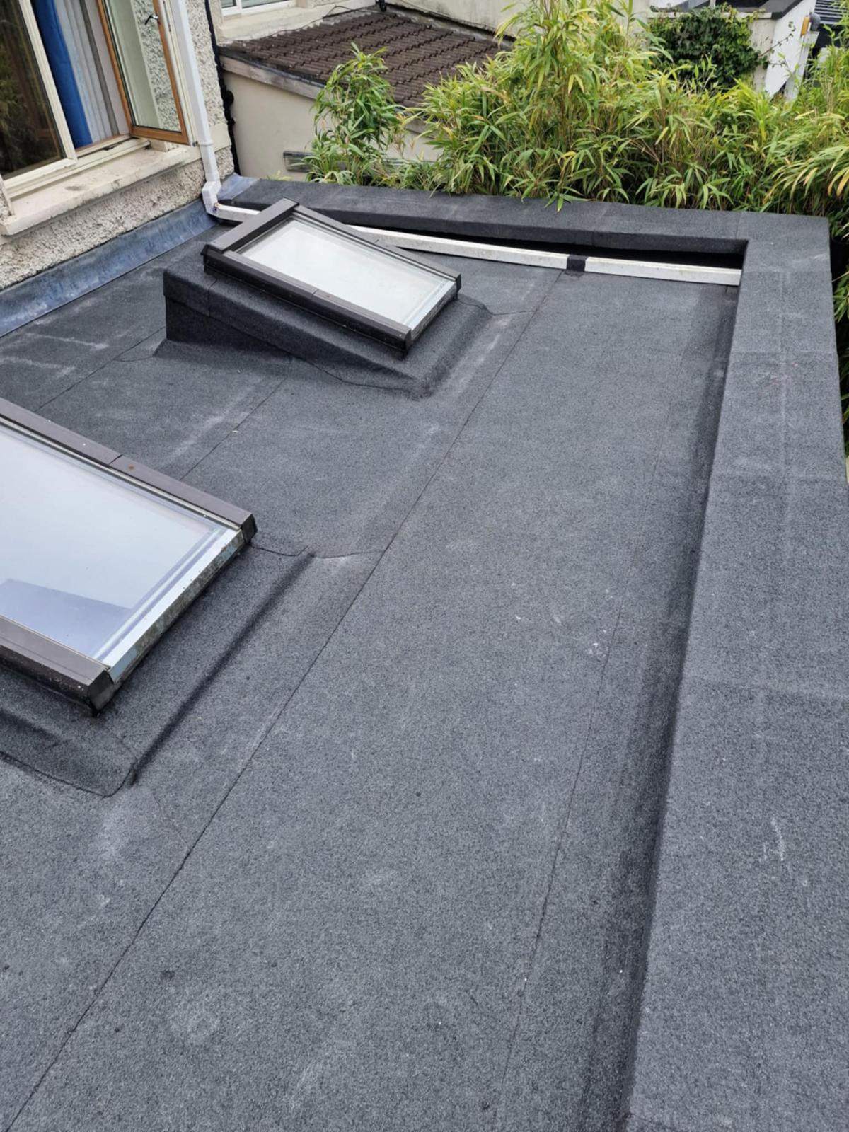 Grey mineral torch-on felt dressed around two roof windows on a flat roof in Walkinstown, Dublin 12