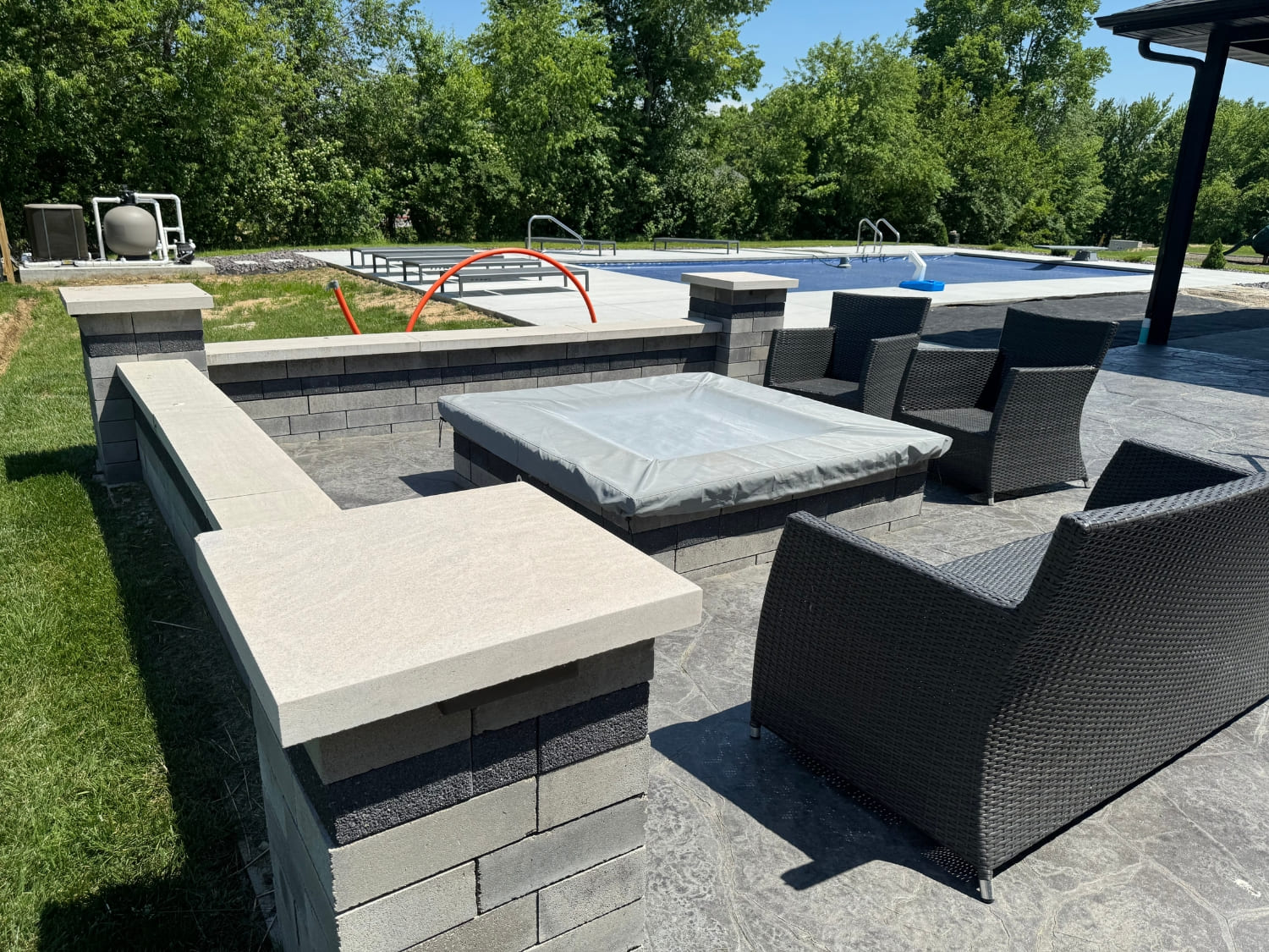 Custom outdoor seating wall and fire pit area beside a pool patio