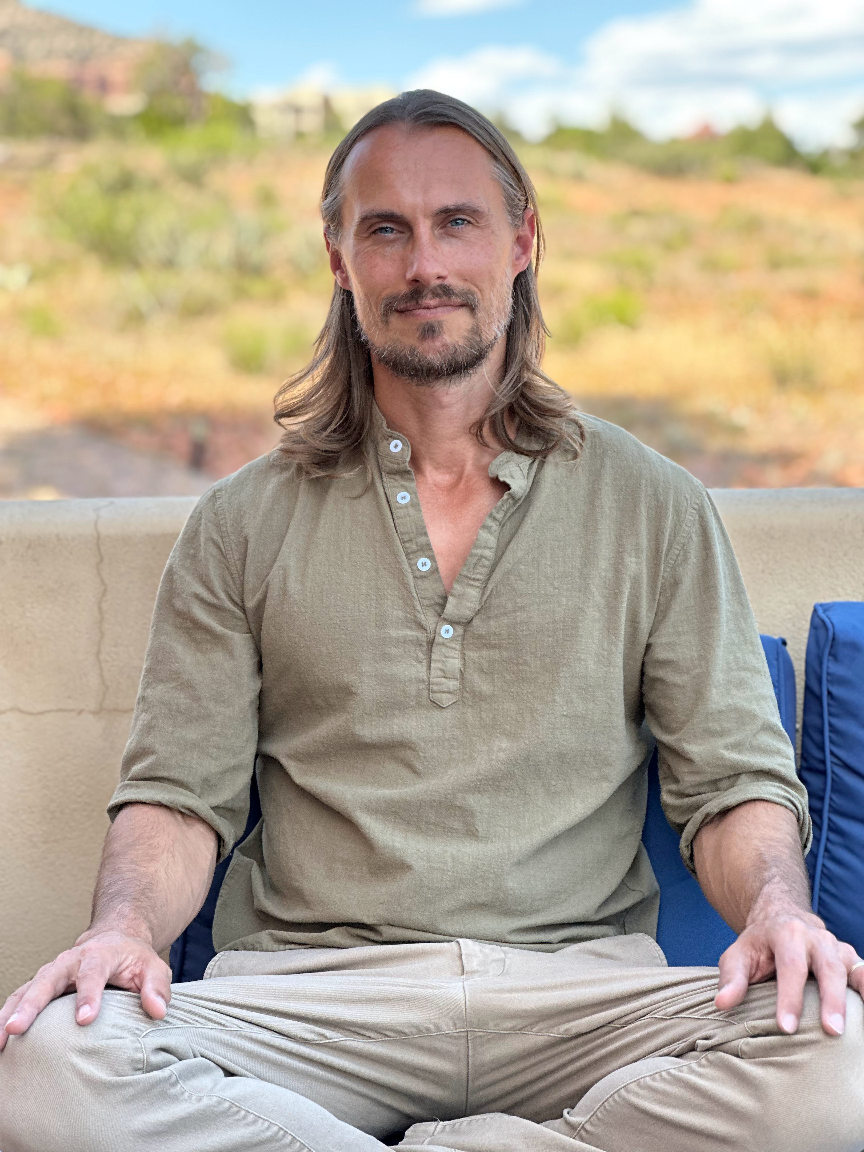 Dr. AJ Karlovich seated cross-legged, hands on knees, facing the camera