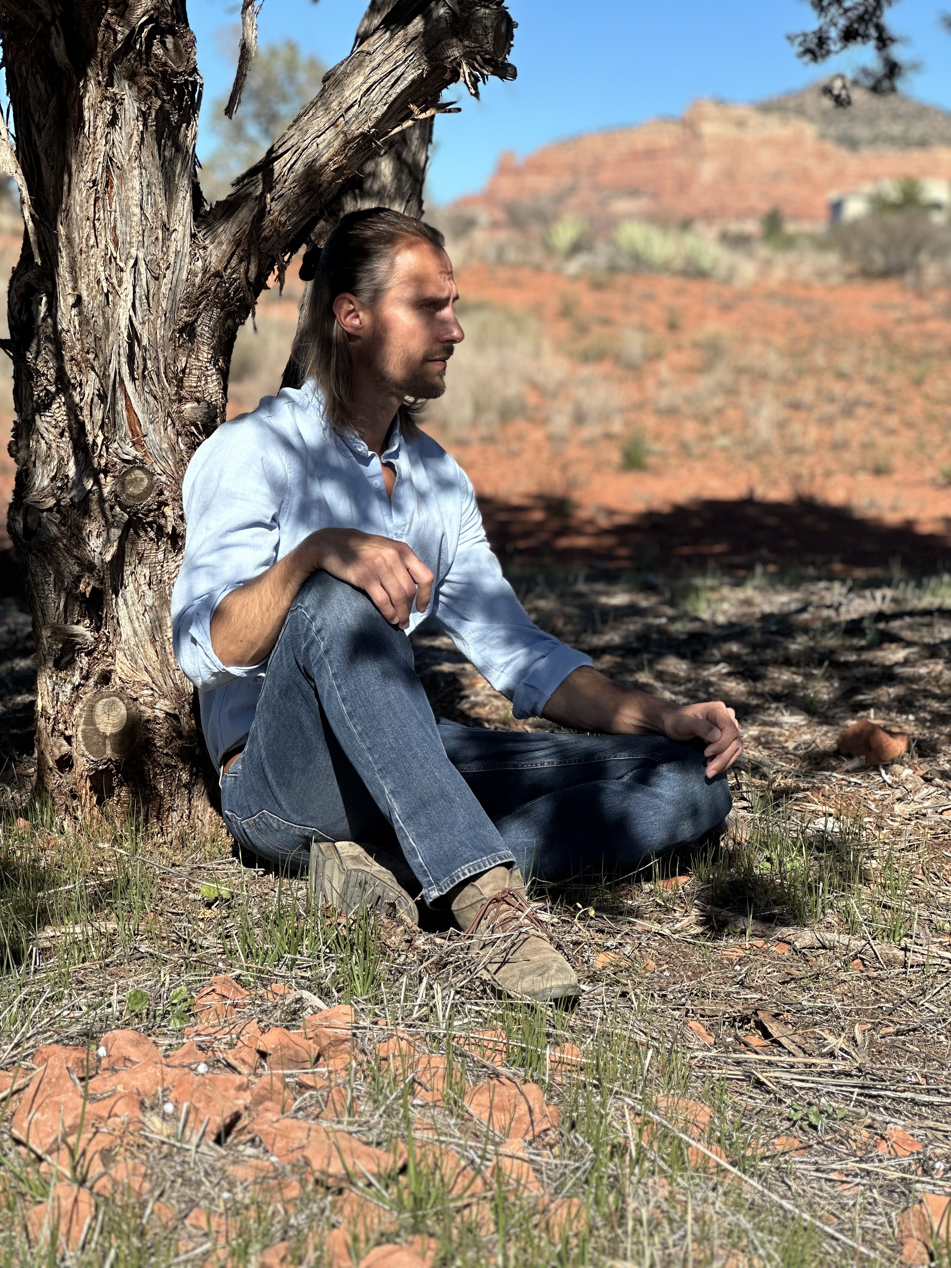 Dr. AJ Karlovich seated under a tree in a desert landscape