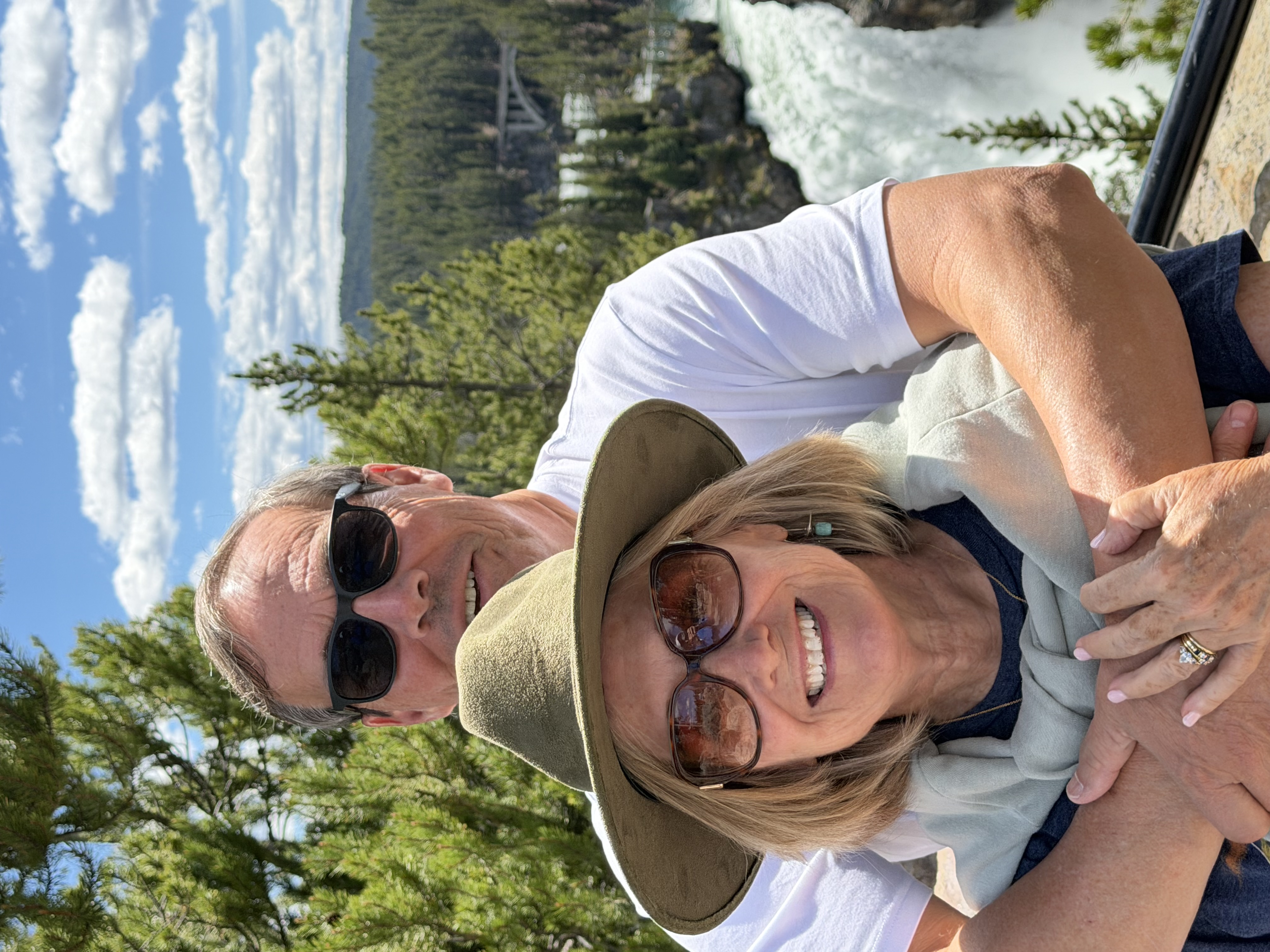 Couple posing together near a waterfall.