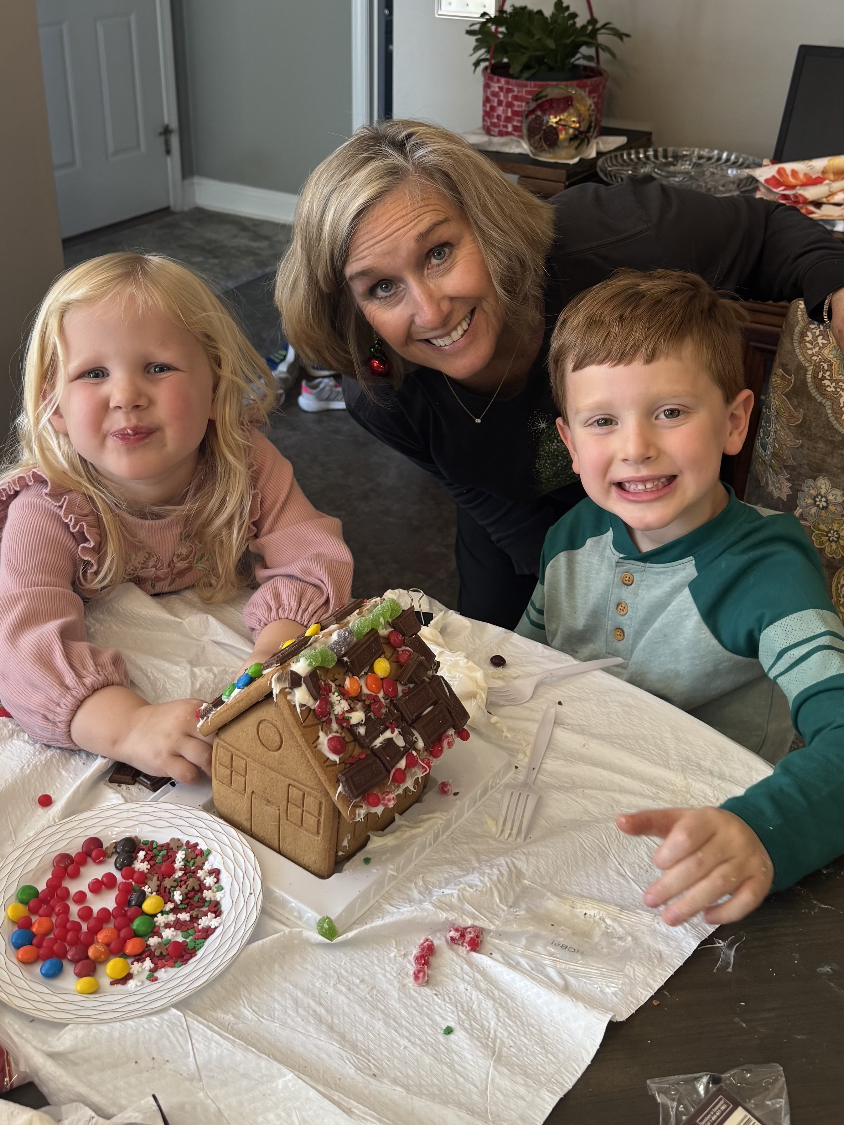 Family decorating a gingerbread house together.