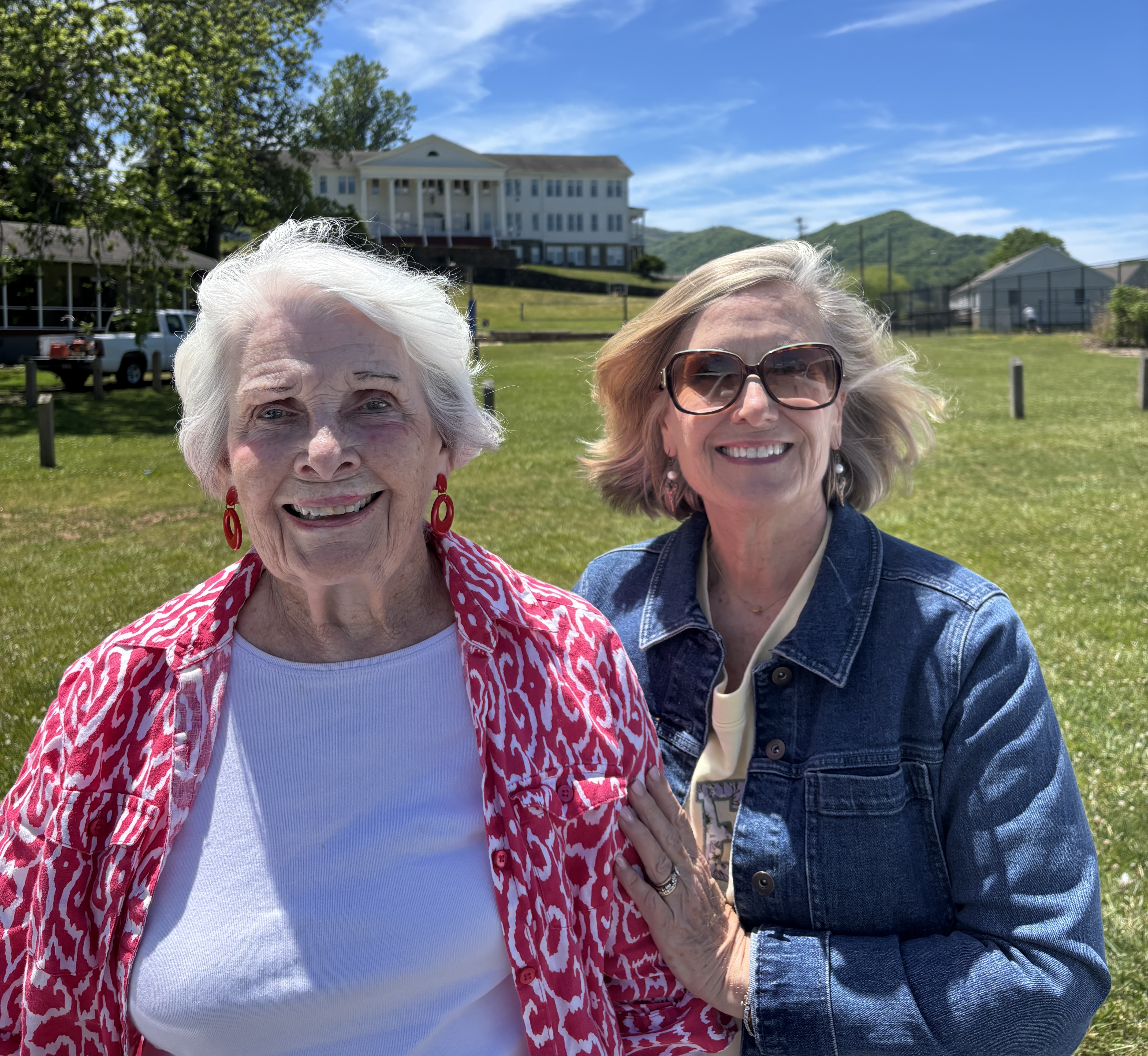 Two women standing outdoors on a sunny day.