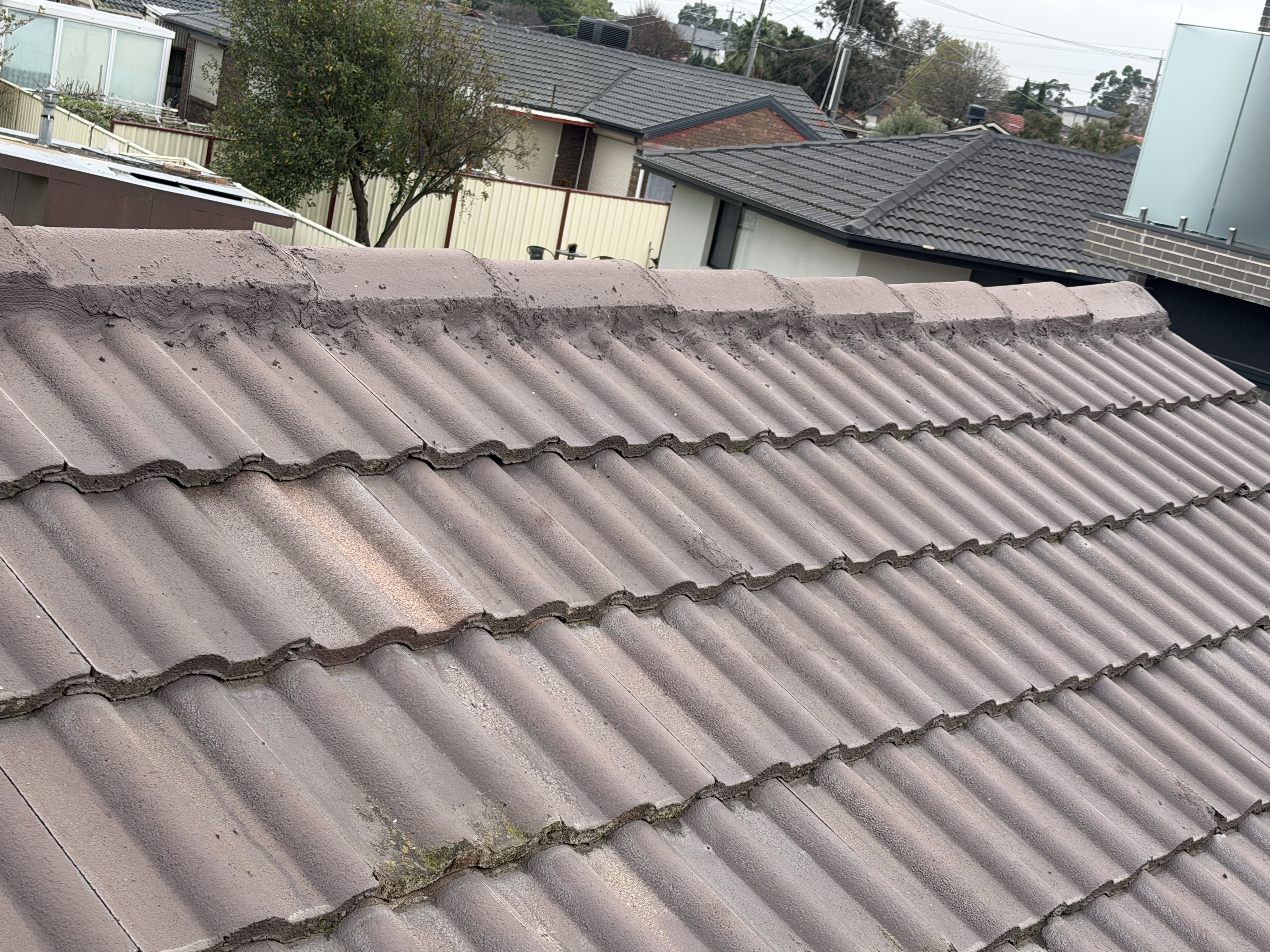 Botched roof job with smeared cement mortar and cracked ridge capping