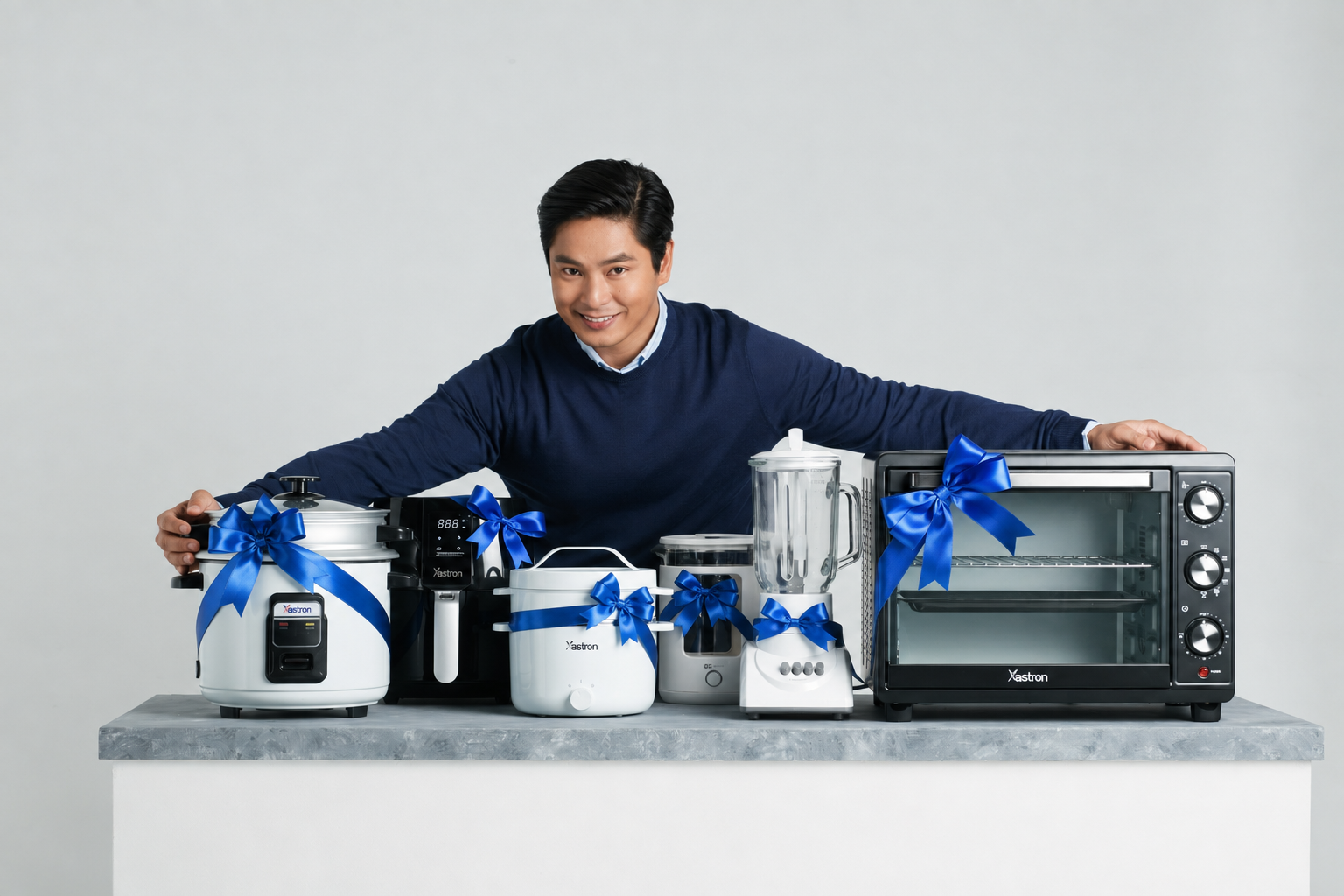Coco Martin with full lineup of Astron appliances including rice cooker, coffee maker, blender, and toaster oven with blue ribbons