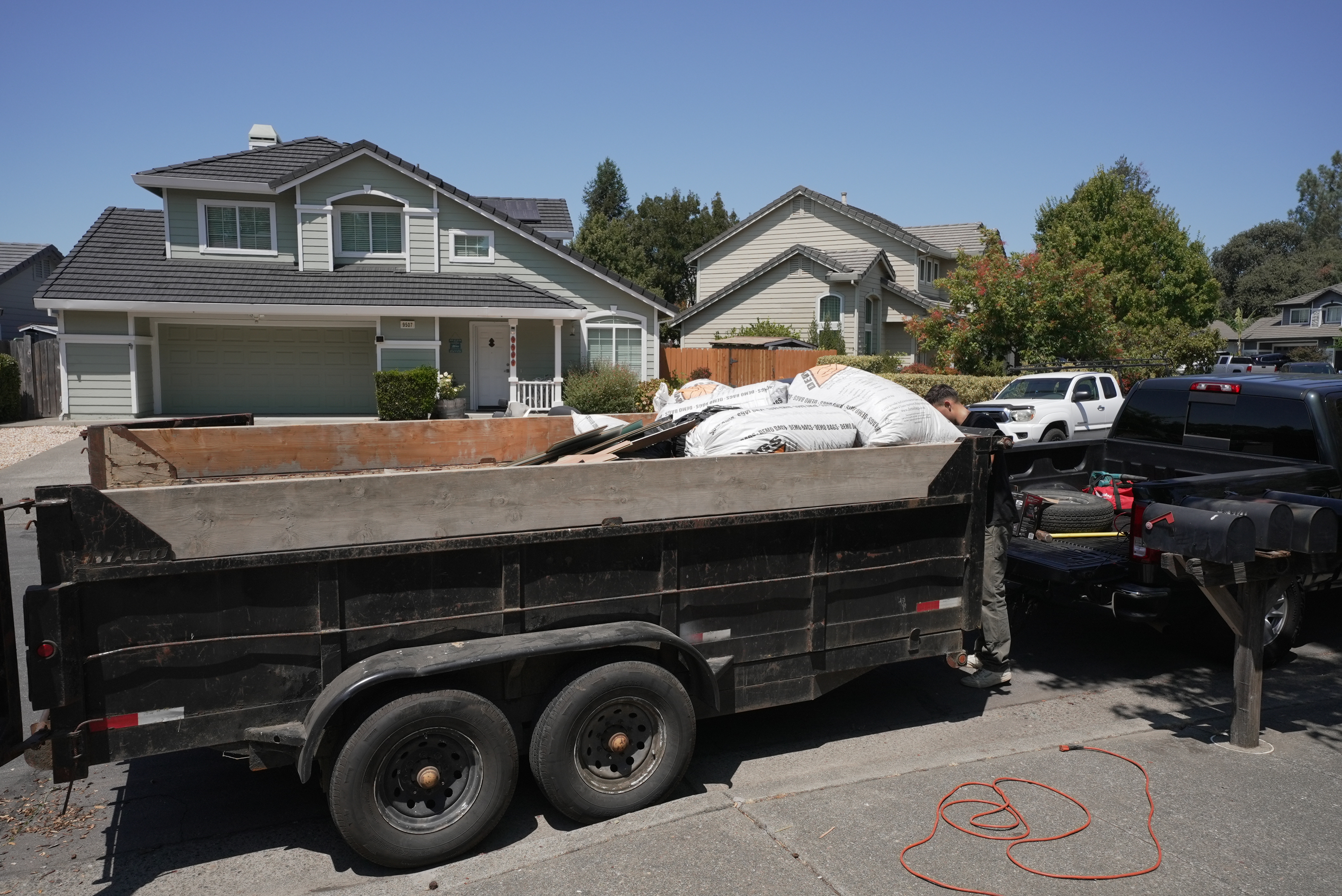 Junk removal truck trailer loaded with debris bags and construction waste in residential Sonoma street