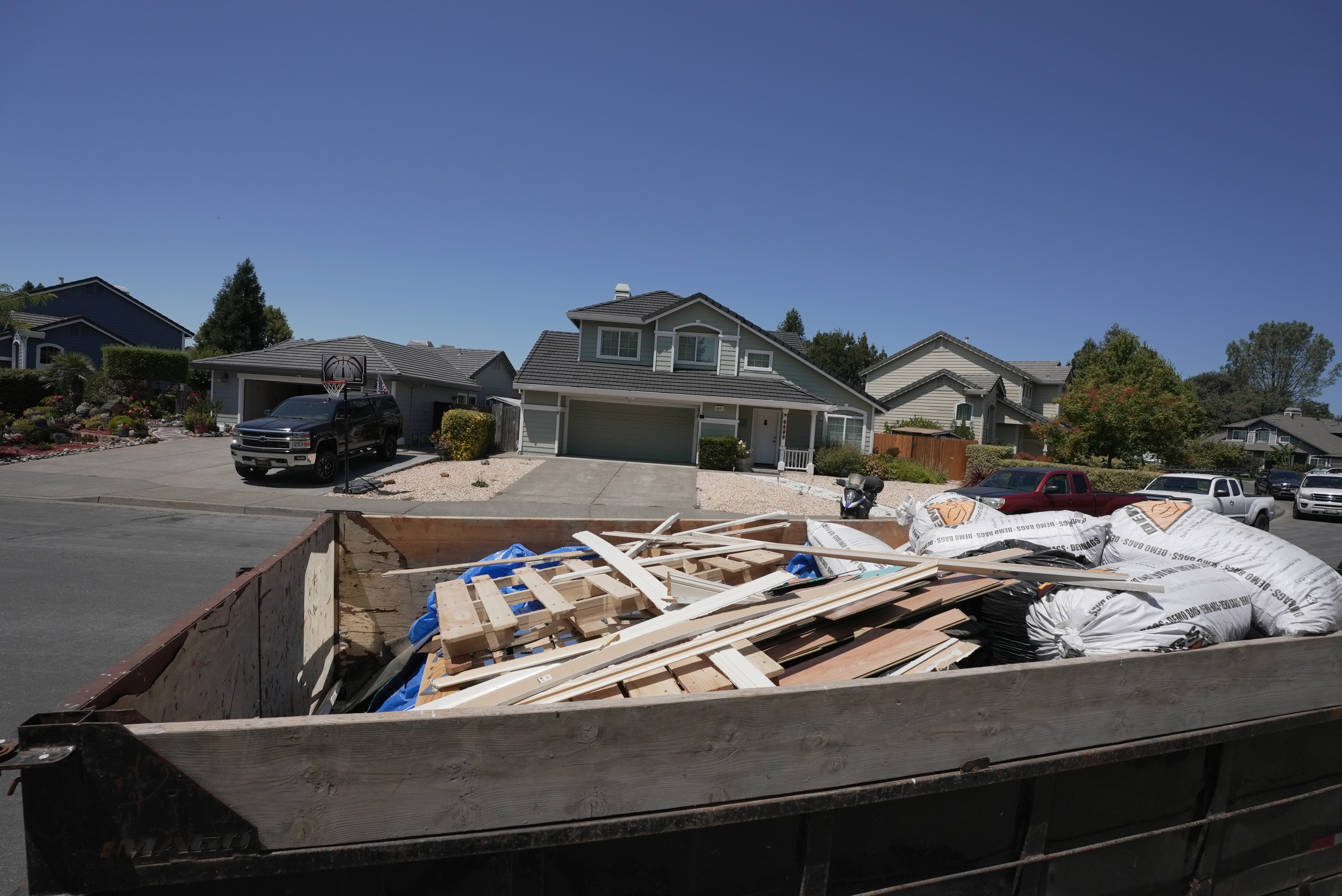 Dumpster trailer fully loaded with construction debris pallets and demo bags in Sonoma neighborhood