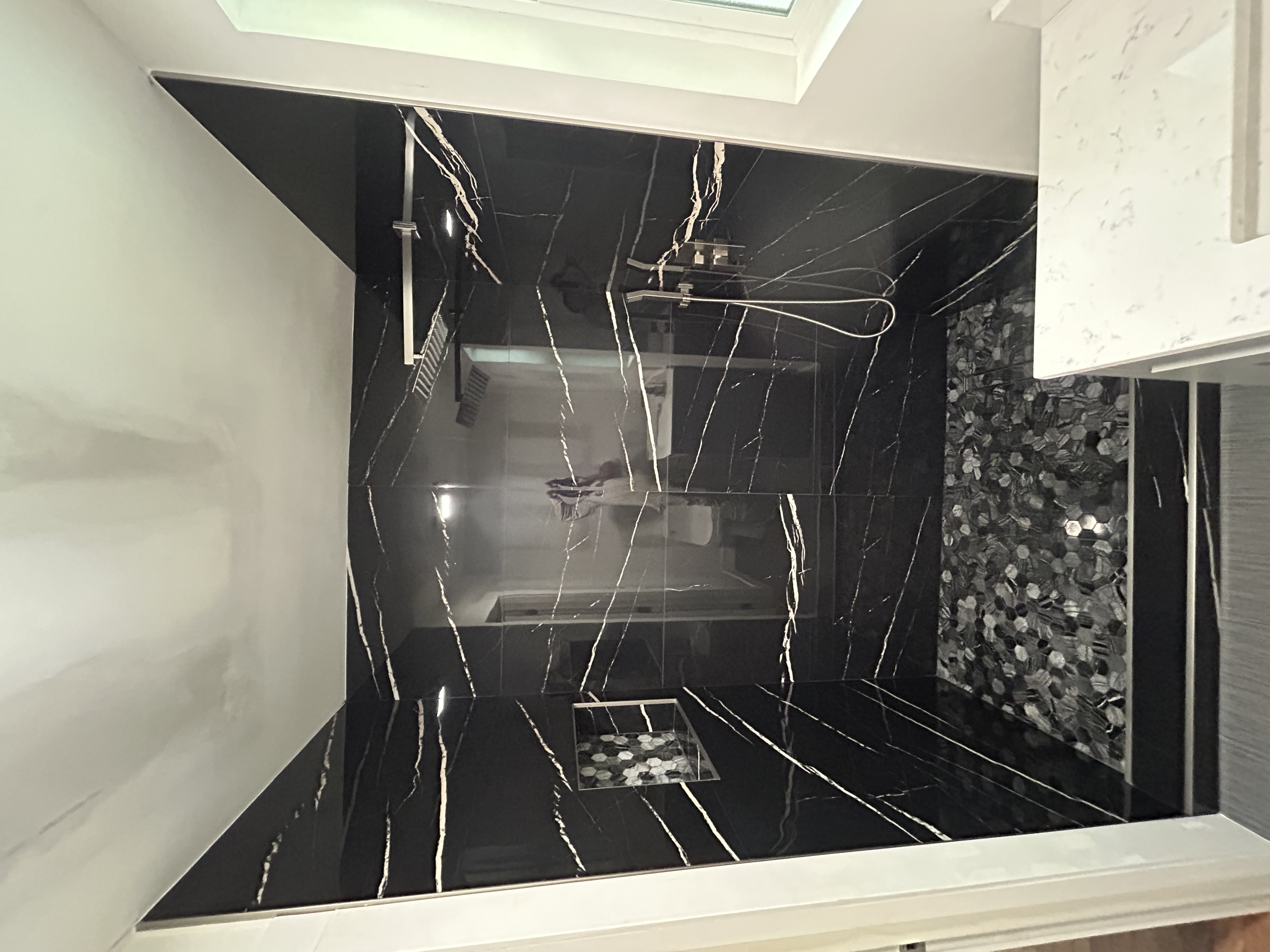 Black marble shower with gold veining and modern fixtures in remodeled Portland bathroom