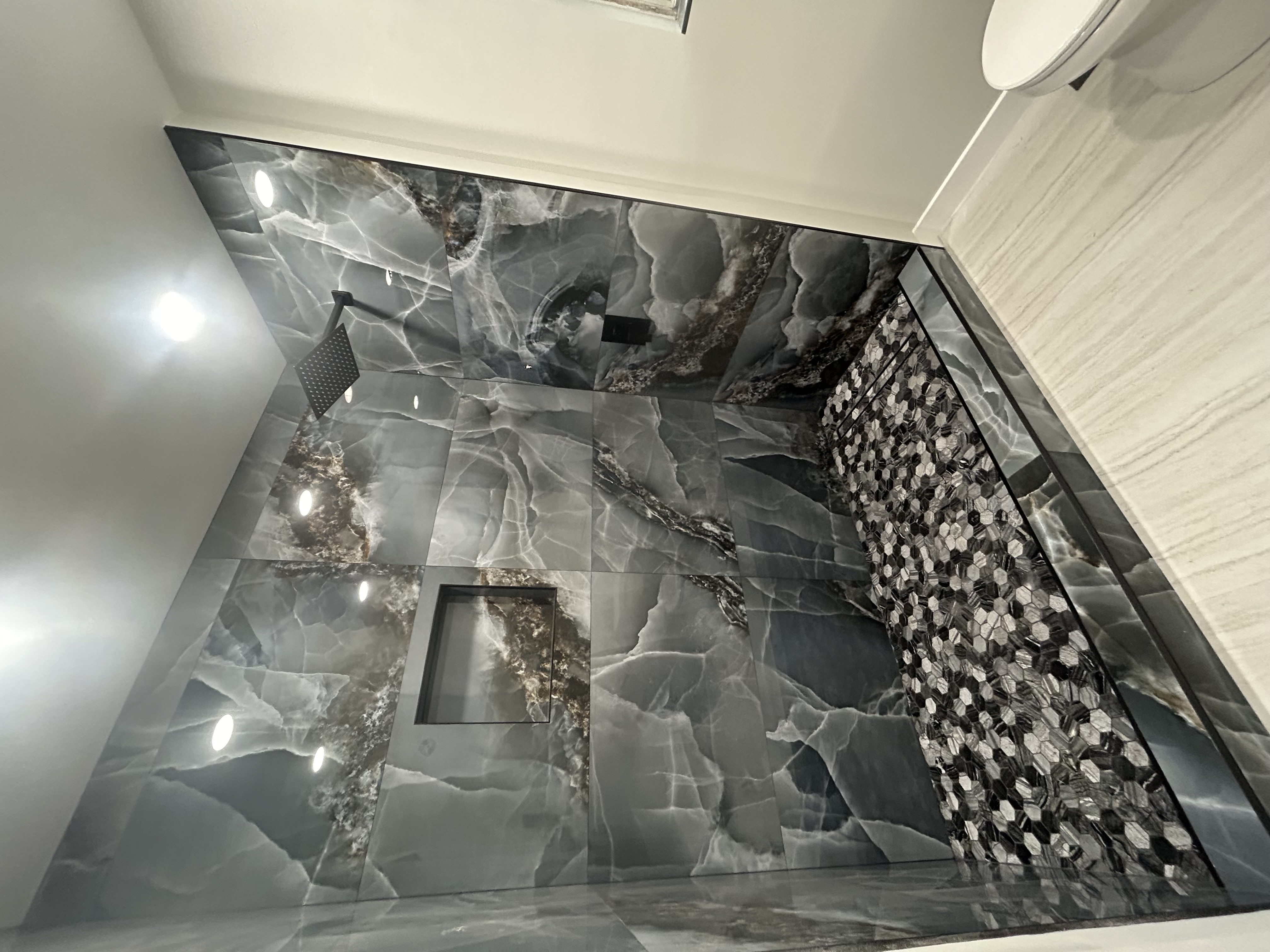 Custom marble tile shower with hexagon accent wall and rainfall showerhead in Portland bathroom remodel