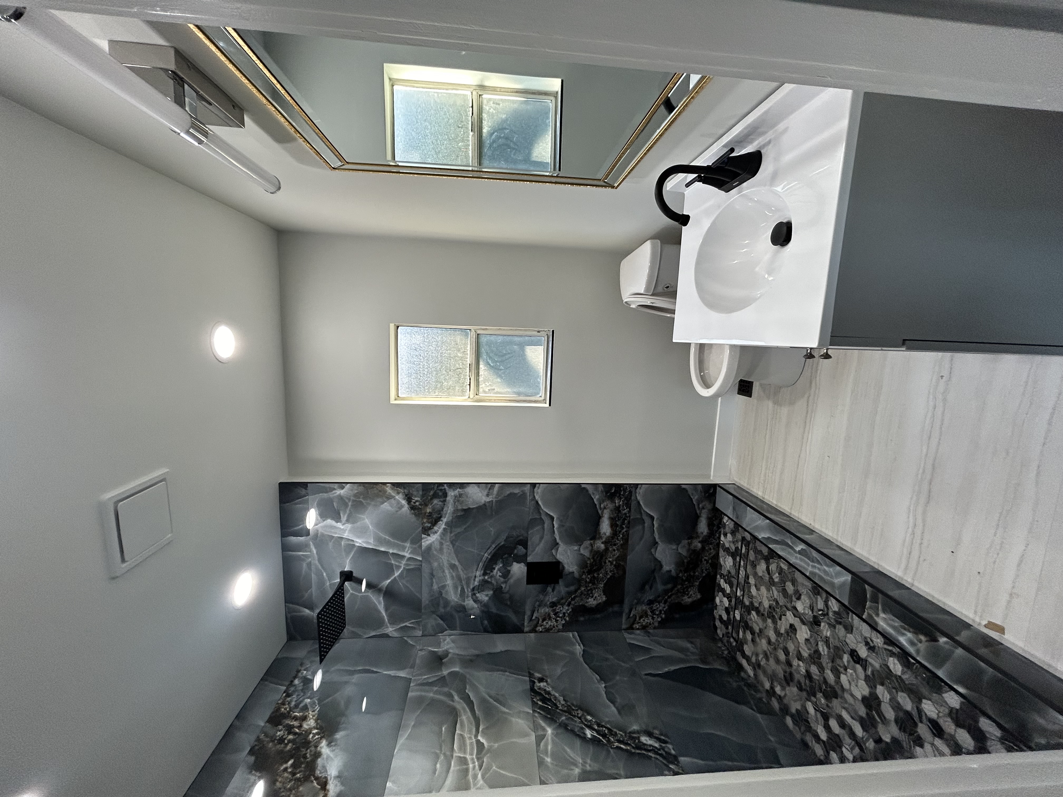 Completed bathroom remodel with marble tile walls, modern fixtures, and clean finishes